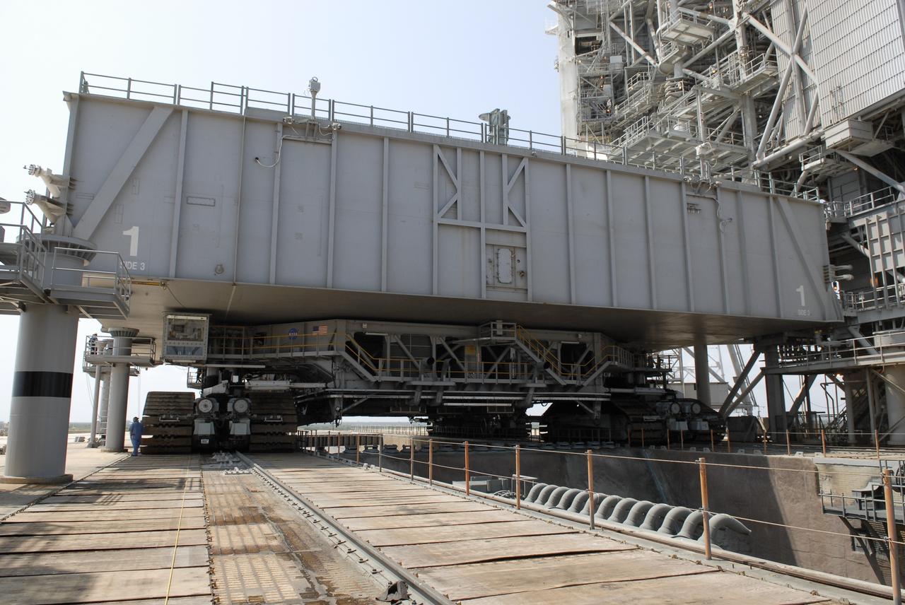 CAPE CANAVERAL, Fla. – At NASA's Kennedy Space Center in Florida, the mobile launcher platform that was turned over from the shuttle program to the Constellation Program last month is being moved from Kennedy's Launch Pad 39B via the crawler-transporter underneath. Here, the platform and crawler can be seen straddling the flame trench on the launch pad.  The platform will be rolled into the Vehicle Assembly Building's High Bay 3 in preparation for the Ares I-X flight test this summer. Ares I-X is the test vehicle for the Ares I, which is part of the Constellation Program to return men to the moon and beyond.  Ground Control System hardware was installed in MLP-1 in December 2008.  The platform was moved to the launch pad to check out the installed hardware with the Launch Control Center Firing Room 1 equipment, using the actual circuits that will be used when the fully stacked Ares I-X vehicle is rolled out later this year for launch.  Photo credit: NASA/Kim Shiflett