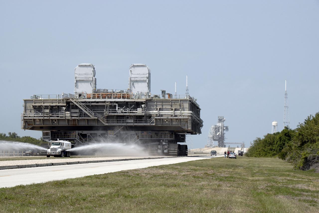 CAPE CANAVERAL, Fla. – At NASA's Kennedy Space Center in Florida, a water truck continues to spray the dry crawlerway in front of the crawler-transporter as it moves the mobile launcher platform on top away from Kennedy's Launch pad 39B.  The platform, turned over from the shuttle program to the Constellation Program last month, will be rolled into the Vehicle Assembly Building's High Bay 3 in preparation for the Ares I-X flight test this summer.  Ares I-X is the test vehicle for the Ares I, which is part of the Constellation Program to return men to the moon and beyond.  Ground Control System hardware was installed in MLP-1 in December 2008.  The platform was moved to the launch pad to check out the installed hardware with the Launch Control Center Firing Room 1 equipment, using the actual circuits that will be used when the fully stacked Ares I-X vehicle is rolled out later this year for launch.  Photo credit: NASA/Kim Shiflett