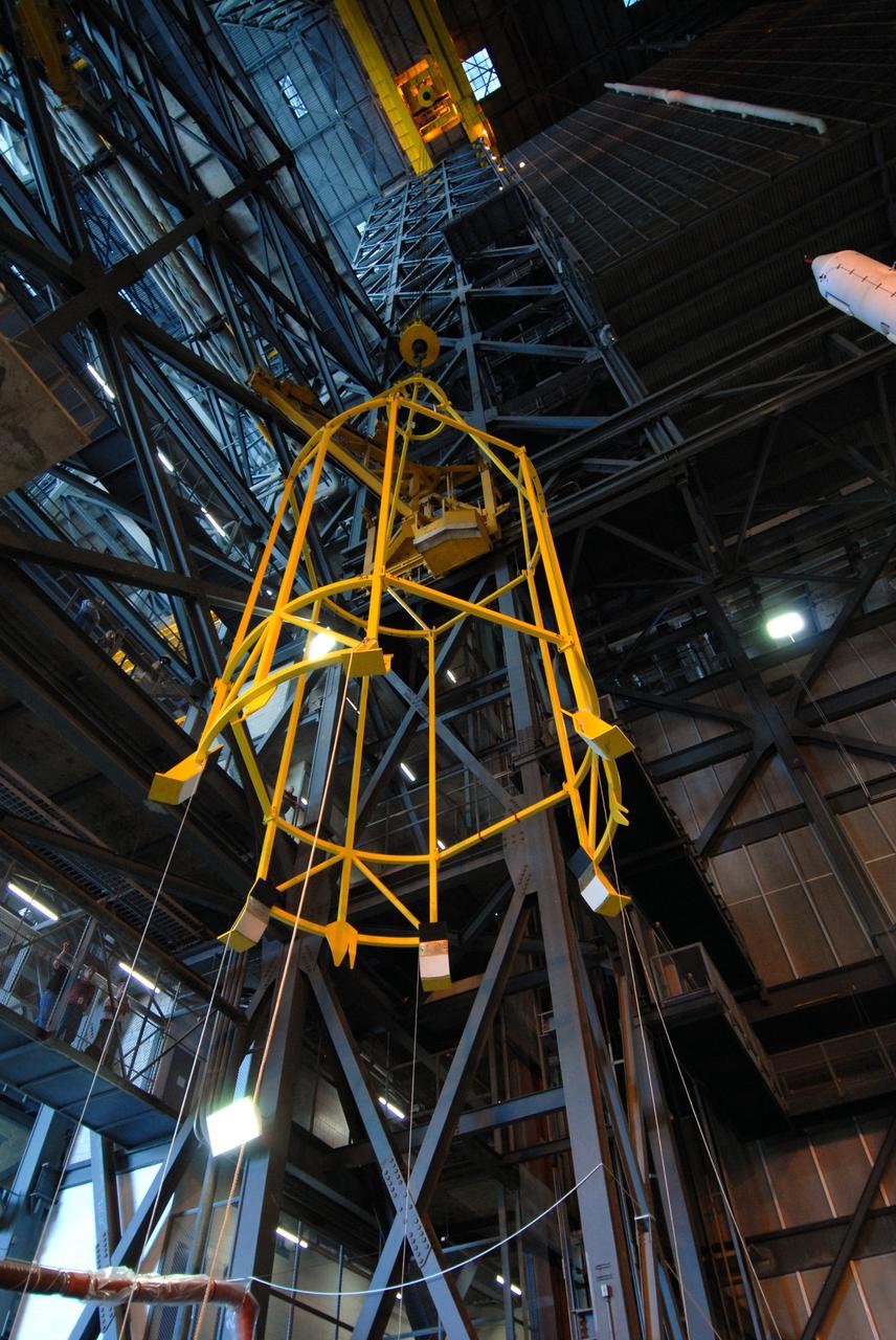 CAPE CANAVERAL, Fla. ––  In High Bay 4 of the Vehicle Assembly Building at NASA's Kennedy Space Center in Florida, the yellow framework at left, nicknamed the "birdcage," is lifted high above the floor for a fit check with the Crew Module, or CM, and Launch Abort System, or LAS, assembly nearby for the Ares I-X rocket.   Ares I-X is the flight test for the Ares I. The I-X flight will provide NASA an early opportunity to test and prove hardware, facilities and ground operations associated with Ares I.  The launch of the 327-foot-tall, full-scale Ares I-X is targeted for July 2009.  Photo credit: NASA/Jack Pfaller