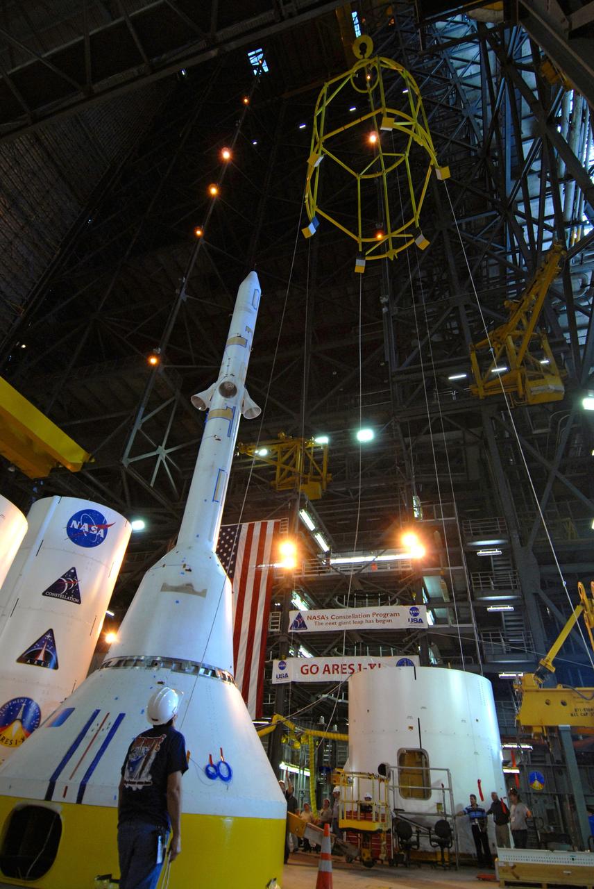 CAPE CANAVERAL, Fla. ––  In High Bay 4 of the Vehicle Assembly Building at NASA's Kennedy Space Center in Florida, the yellow framework at top, nicknamed the "birdcage," is lifted high above the floor for a fit check with the Crew Module, or CM, and Launch Abort System, or LAS, assembly at lower left for the Ares I-X rocket. Ares I-X is the flight test for the Ares I. The I-X flight will provide NASA an early opportunity to test and prove hardware, facilities and ground operations associated with Ares I.  The launch of the 327-foot-tall, full-scale Ares I-X is targeted for July 2009.  Photo credit: NASA/Jack Pfaller