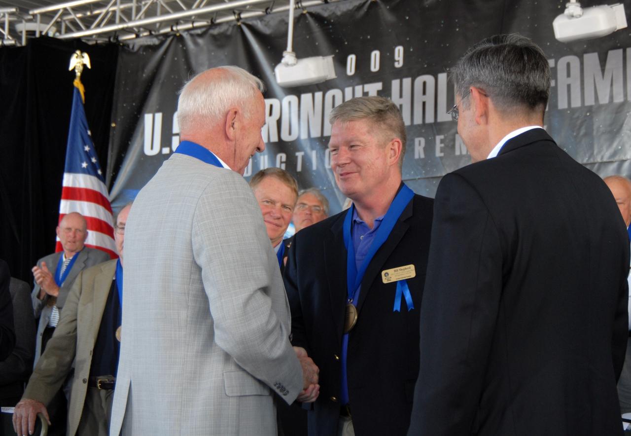 CAPE CANAVERAL, Fla. –– At left, U.S. Astronaut Hall of Fame member Al Worden congratulates astronaut William Shepherd (center) on his induction into the hall of fame during the ceremony held at NASA's Kennedy Space Center Visitor Complex in Florida. At right is Center Director Bob Cabana, who is a member of the hall of fame. Shepherd was commander of the first crew to live aboard the International Space Station. The ceremony took place May 2. More than 20 hall of fame astronauts attended, including Scott Carpenter, Walt Cunningham, Jim Lovell and Bob Crippen. Photo credit: NASA/Jim Grossmann