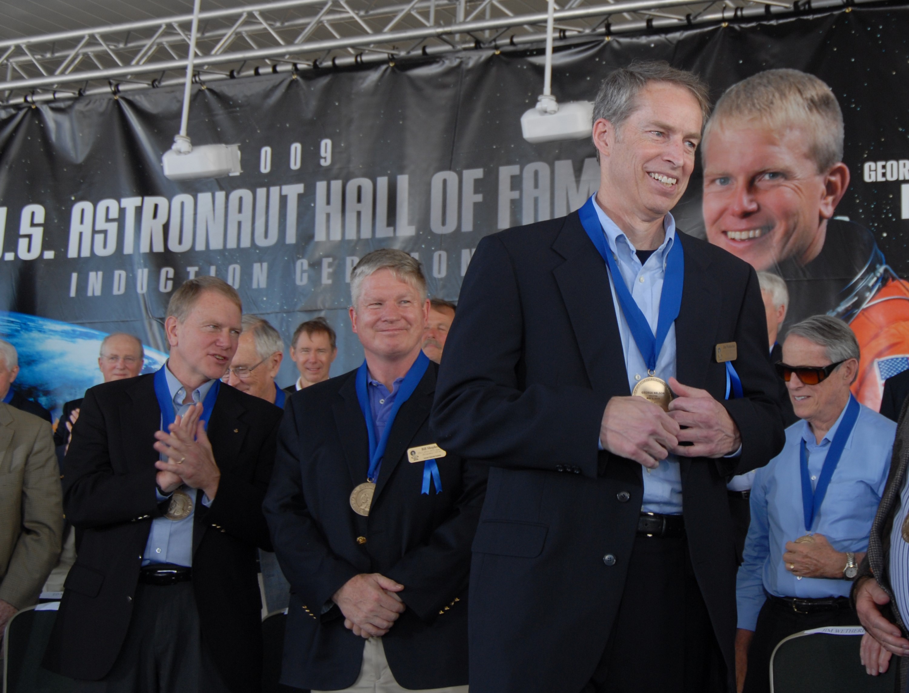 CAPE CANAVERAL, Fla. –– The three newest inductees into the U.S. Astronaut Hall of Fame share the stage after receiving their medals.  From left are George "Pinky" Nelson, who was one of only six space shuttle astronauts to fly untethered in space using NASA's Manned Maneuvering Unit; William Shepherd, who was commander of the first crew to live aboard the International Space Station; and James Wetherbee, who was commander of the longest-docked shuttle-Mir mission. The ceremony was held at NASA's Kennedy Space Center Visitor Complex in Florida. The ceremony took place May 2. More than 20 hall of fame astronauts attended, including Scott Carpenter, Walt Cunningham, Jim Lovell and Bob Crippen. Photo credit: NASA/Jim Grossmann