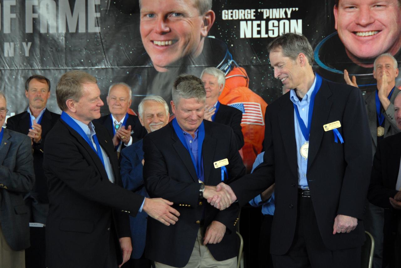 CAPE CANAVERAL, Fla. –– The three newest inductees into the U.S. Astronaut Hall of Fame congratulate each other after receiving their medals. From left are George "Pinky" Nelson, who was one of only six space shuttle astronauts to fly untethered in space using NASA's Manned Maneuvering Unit; William Shepherd, who was commander of the first crew to live aboard the International Space Station; and James Wetherbee, who was commander of the longest-docked shuttle-Mir mission.  The ceremony was held at NASA's Kennedy Space Center Visitor Complex in Florida. The ceremony took place May 2. More than 20 hall of fame astronauts attended, including Scott Carpenter, Walt Cunningham, Jim Lovell and Bob Crippen. Photo credit: NASA/Jim Grossmann