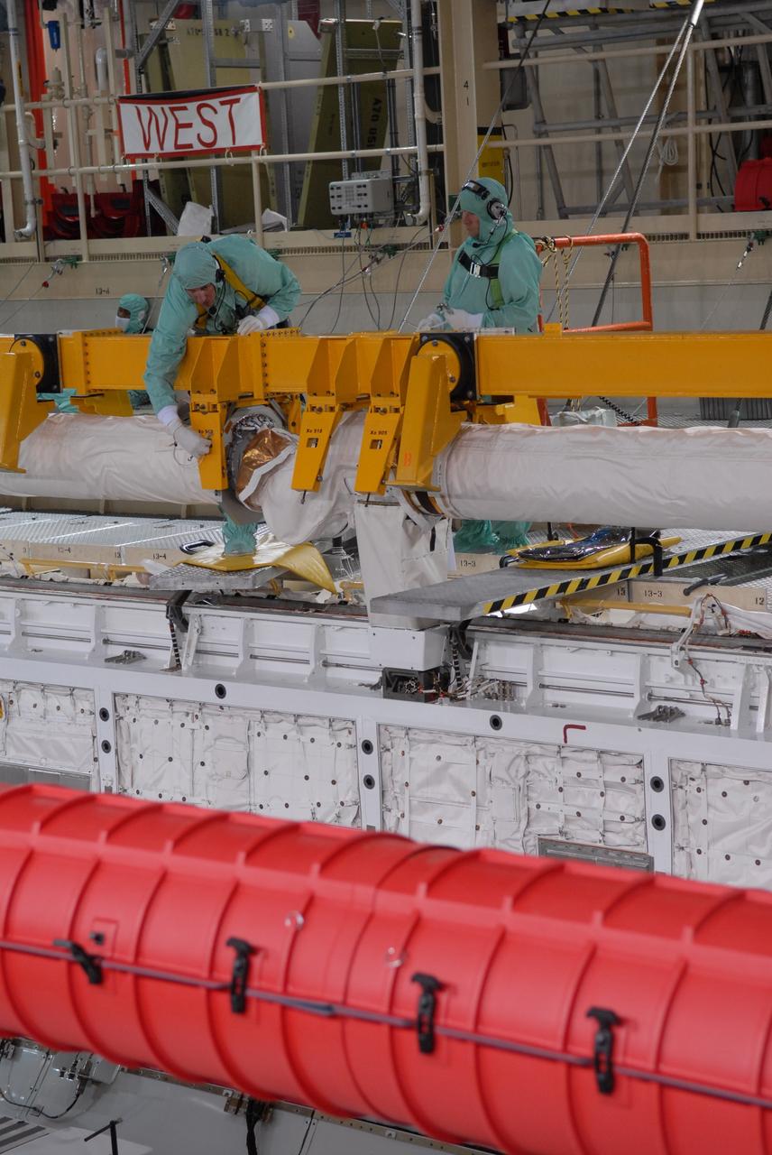 CAPE CANAVERAL, Fla. –  In Orbiter Processing Facility bay 3 at NASA's Kennedy Space Center in Florida, technicians prepare to remove remote manipulator system, or RMS, arm in the payload bay of space shuttle Discovery. The RMS is used to grab, or grapple, the payload as well as retrieve, repair and deploy satellites; provide a mobile extension ladder for spacewalking crewmembers; and be used as an inspection aid to allow flight crew members to view the orbiter’s or payload’s surfaces through a TV camera on the arm. Discovery is targeted to launch Aug. 6 on the STS-128 mission.  Photo credit: NASA/Jack Pfaller
