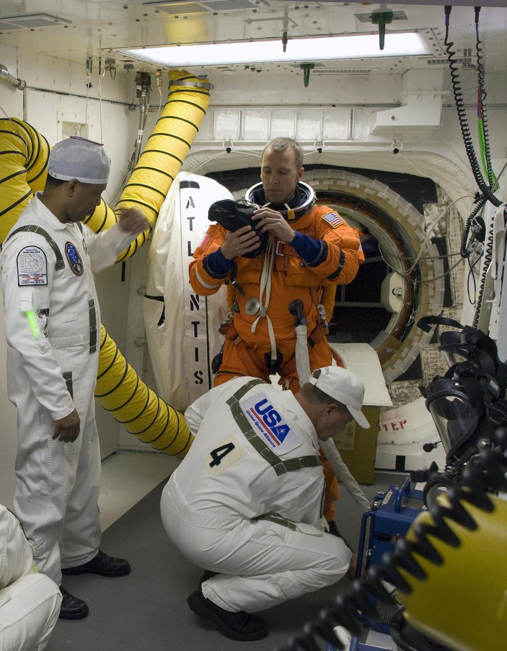 CAPE CANAVERAL, Fla. – In the White Room on Launch Pad 39A at NASA's Kennedy Space Center in Florida, STS-125 Mission Specialist Andrew Feustel is helped by the closeout crew putting on his harness, which includes a parachute pack, before crawling through the open hatch into space shuttle Atlantis. The White Room is at the end of the orbiter access arm on the fixed service structure and provides access into the shuttle. Atlantis' 11-day flight will include five spacewalks to refurbish and upgrade the telescope with state-of-the-art science instruments that will expand Hubble's capabilities and extend its operational lifespan through at least 2014.  The payload includes a Wide Field Camera 3, fine guidance sensor and the Cosmic Origins Spectrograph. Launch of Atlantis on the STS-125 mission is scheduled for 2:01 p.m. May 11 EDT.  Photo credit: NASA/Sandra Joseph-Kevin O'Connell