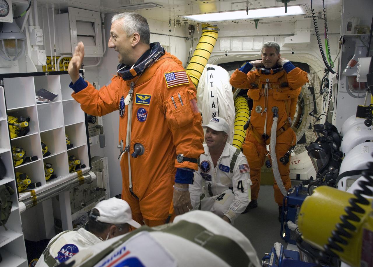 CAPE CANAVERAL, Fla. – In the White Room on Launch Pad 39A at NASA's Kennedy Space Center in Florida, STS-125 Mission Specialist Mike Massimino, left, is next in line to complete preparation of his launch-and-entry suit for launch. At right, Mission Specialist Michael Good is helped with his harness, which includes a parachute pack, before crawling through the open hatch into space shuttle Atlantis. The White Room is at the end of the orbiter access arm on the fixed service structure and provides access into the shuttle. Atlantis' 11-day flight will include five spacewalks to refurbish and upgrade the telescope with state-of-the-art science instruments that will expand Hubble's capabilities and extend its operational lifespan through at least 2014. The payload includes a Wide Field Camera 3, fine guidance sensor and the Cosmic Origins Spectrograph. Launch of Atlantis on the STS-125 mission is scheduled for 2:01 p.m. May 11 EDT. Photo credit: NASA/Sandra Joseph-Kevin O'Connell