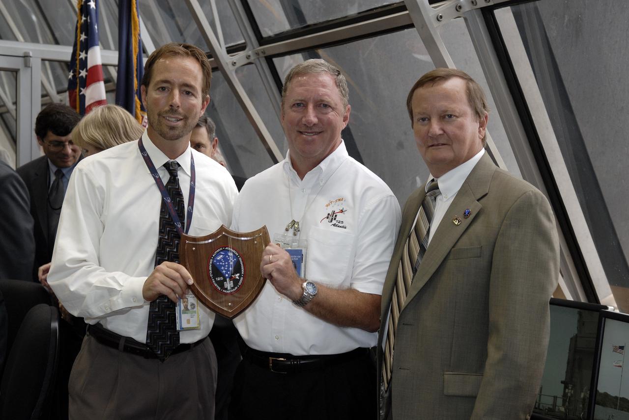 CAPE CANAVERAL, Fla. – In the Firing Room at NASA's Kennedy Space Center in Florida, Steven Hoyle, left, and Russ Brucker, center, receive a VIP award for their efforts associated with the STS-125 mission and NASA's Hubble Space Telescope.  Hoyle is the payload test operations manager with NASA's Goddard Space Flight Center; Brucker is the Atlantis payload project manager with United Space Alliance.  A crew of seven launched today on space shuttle Atlantis to service Hubble. Liftoff was on time at 2:01 p.m. EDT. Atlantis' 11-day flight will include five spacewalks to refurbish and upgrade the telescope with state-of-the-art science instruments that will expand Hubble's capabilities and extend its operational lifespan through at least 2014.  The payload includes a Wide Field Camera 3, fine guidance sensor and the Cosmic Origins Spectrograph.  Photo credit: NASA/Kim Shiflett