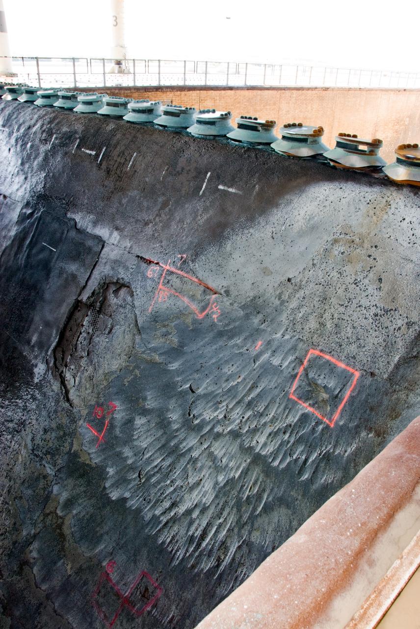 CAPE CANAVERAL, Fla. – A closeup of damage found in the Launch Pad 39A flame trench at NASA's Kennedy Space Center in Florida after launch of space shuttle Atlantis on the STS-125 mission May 11. About 25 square feet of Fondue Fyre broke off from the north side of the solid rocket booster flame deflector. The flame trench channels the flames and smoke exhaust of the shuttle's solid rocket boosters away from the space shuttle.   Fondue Fyre is a fire-resistant concrete-like material.  Some pneumatic lines (gaseous nitrogen, pressurized air) in the area also were damaged. Preliminary assessments indicated technicians can make repairs to the pad in time to support space shuttle Endeavour's targeted June 13 launch.  Photo credit: NASA/Kim Shiflett
