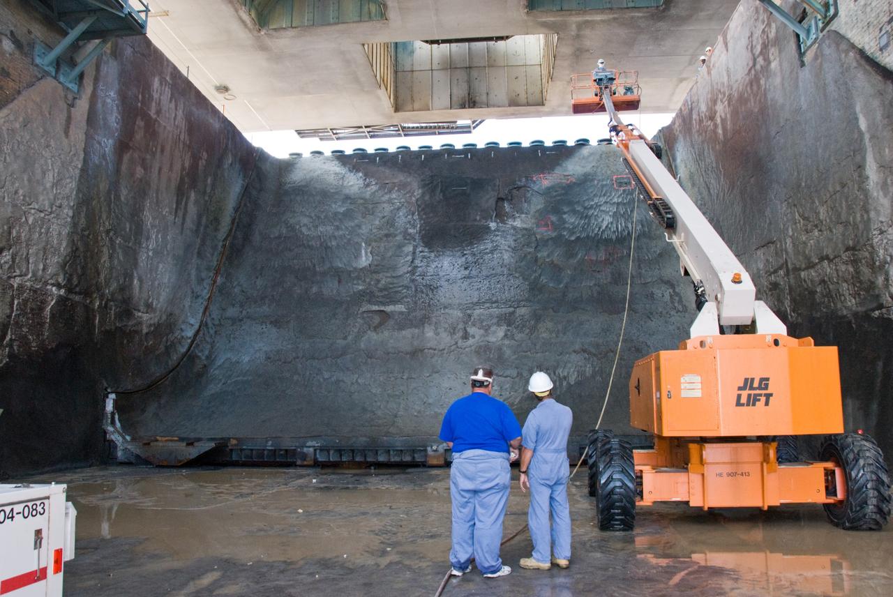 CAPE CANAVERAL, Fla. – In Launch Pad 39A lame trench at NASA's Kennedy Space Center in Florida, workers document damage found  after launch of space shuttle Atlantis on the STS-125 mission May 11. About 25 square feet of Fondue Fyre broke off from the north side of the solid rocket booster flame deflector. The flame trench channels the flames and smoke exhaust of the shuttle's solid rocket boosters away from the space shuttle.    Fondue Fyre is a fire-resistant concrete-like material.  Some pneumatic lines (gaseous nitrogen, pressurized air) in the area also were damaged. Preliminary assessments indicated technicians can make repairs to the pad in time to support space shuttle Endeavour's targeted June 13 launch.  Photo credit: NASA/Kim Shiflett
