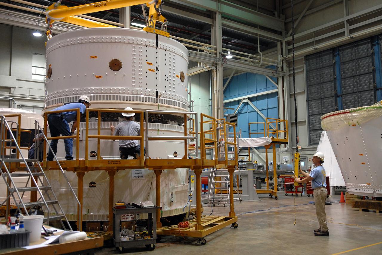 CAPE CANAVERAL, Fla. – In the Assembly and Refurbishment Facility at NASA's Kennedy Space Center in Florida, technicians keep watch as a crane lowers the Ares I-X forward skirt toward the forward skirt extension for mating. The forward skirt is the initial piece of first-stage hardware in preparation for the August 2009 test flight of NASA's next-generation spacecraft and launch vehicle system. Built entirely of armored steel, the 14,000-pound segment is seven feet tall and 12-1/4 feet wide.   Photo credit: NASA/Tim Jacobs
