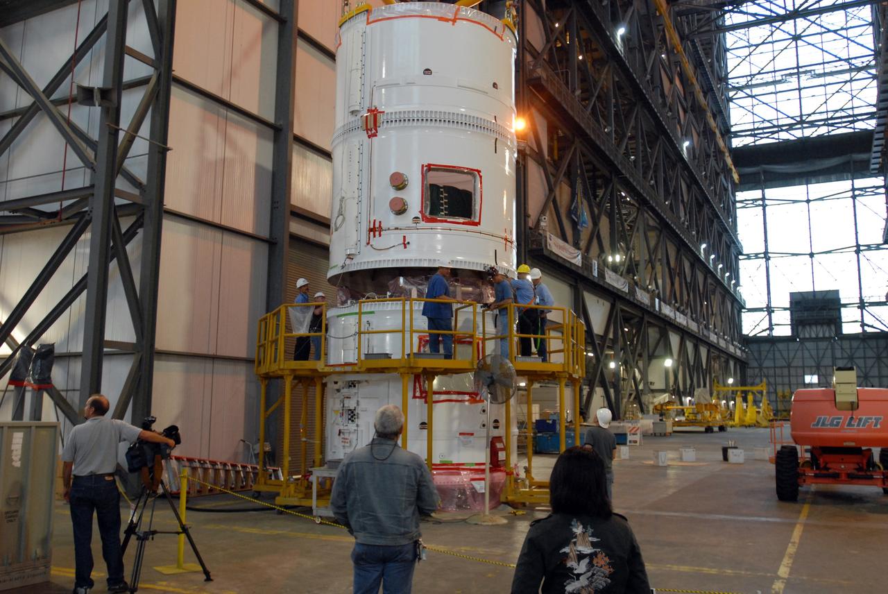 CAPE CANAVERAL, Fla. – In the transfer aisle of the Vehicle Assembly Building at NASA's Kennedy Space Center in Florida, a crane lowers the conjoined forward and center segments of the fifth segment simulator for the Ares I-X onto the simulator’s aft segment. Ares I-X is the test vehicle for the Ares I, a component of the Constellation Program to return men to the moon and beyond. Ares I is the essential core of a safe, reliable, cost-effective space transportation system that eventually will carry crewed missions back to the moon, on to Mars and out into the solar system. The launch of the Ares I-X flight test is targeted for August 2009.  Photo credit: NASA/Jim Grossmann