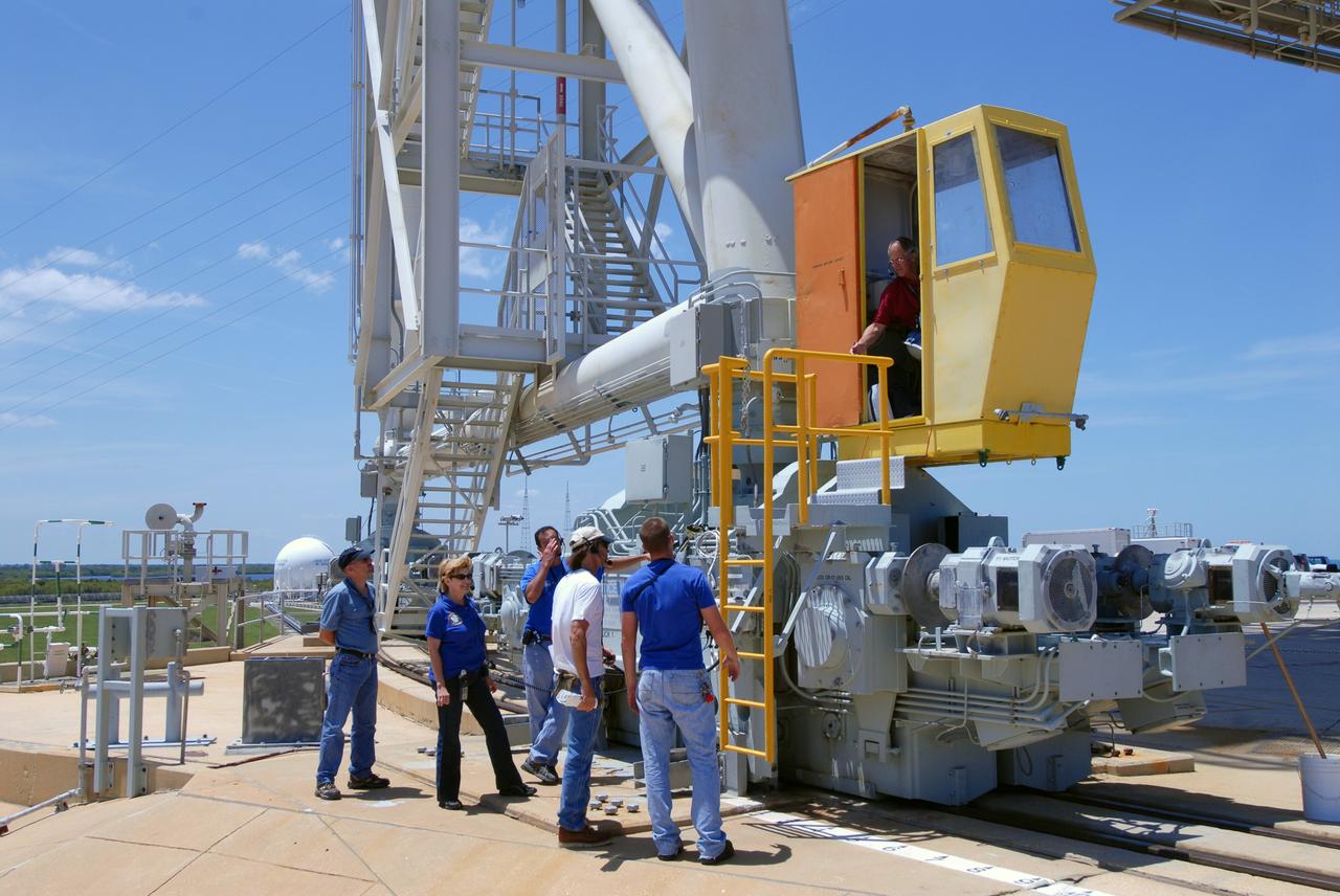 CAPE CANAVERAL, Fla. – On Launch Pad 39A at NASA's Kennedy Space Center in Florida, workers talk to the driver of the rotating service structure, or RSS, before it is moved around space shuttle Endeavour. The RSS provides protected access to the shuttle for changeout and servicing of payloads at the pad. The structure is supported by a rotating bridge that pivots about a vertical axis on the west side of the pad's flame trench. The RSS rotates through 120 degrees (one-third of a circle) on a radius of 160 feet. Support for the outer end of the bridge is provided by two eight-wheel, motor-driven trucks that move along circular twin rails installed flush with the pad surface. The track crosses the flame trench on a permanent bridge. Endeavour is targeted to launch June 13 on its STS-127 mission to the International Space Station. Photo credit: NASA/Tim Jacobs