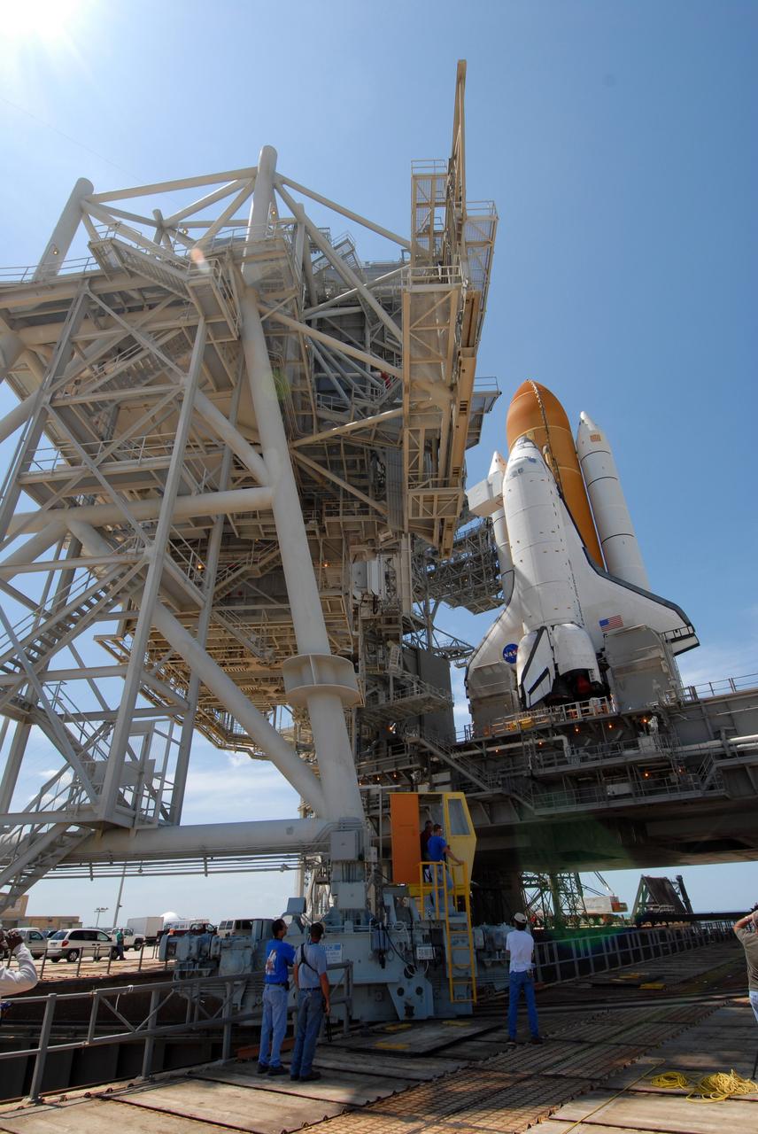 CAPE CANAVERAL, Fla. – On Launch Pad 39A at NASA's Kennedy Space Center in Florida, workers keep watch as the rotating service structure, or RSS, is moved to enclose space shuttle Endeavour. The RSS provides protected access to the shuttle for changeout and servicing of payloads at the pad. The structure is supported by a rotating bridge that pivots about a vertical axis on the west side of the pad's flame trench. The RSS rotates through 120 degrees (one-third of a circle) on a radius of 160 feet. Support for the outer end of the bridge is provided by two eight-wheel, motor-driven trucks that move along circular twin rails installed flush with the pad surface. The track crosses the flame trench on a permanent bridge. Endeavour is targeted to launch June 13 on its STS-127 mission to the International Space Station. Photo credit: NASA/Tim Jacobs