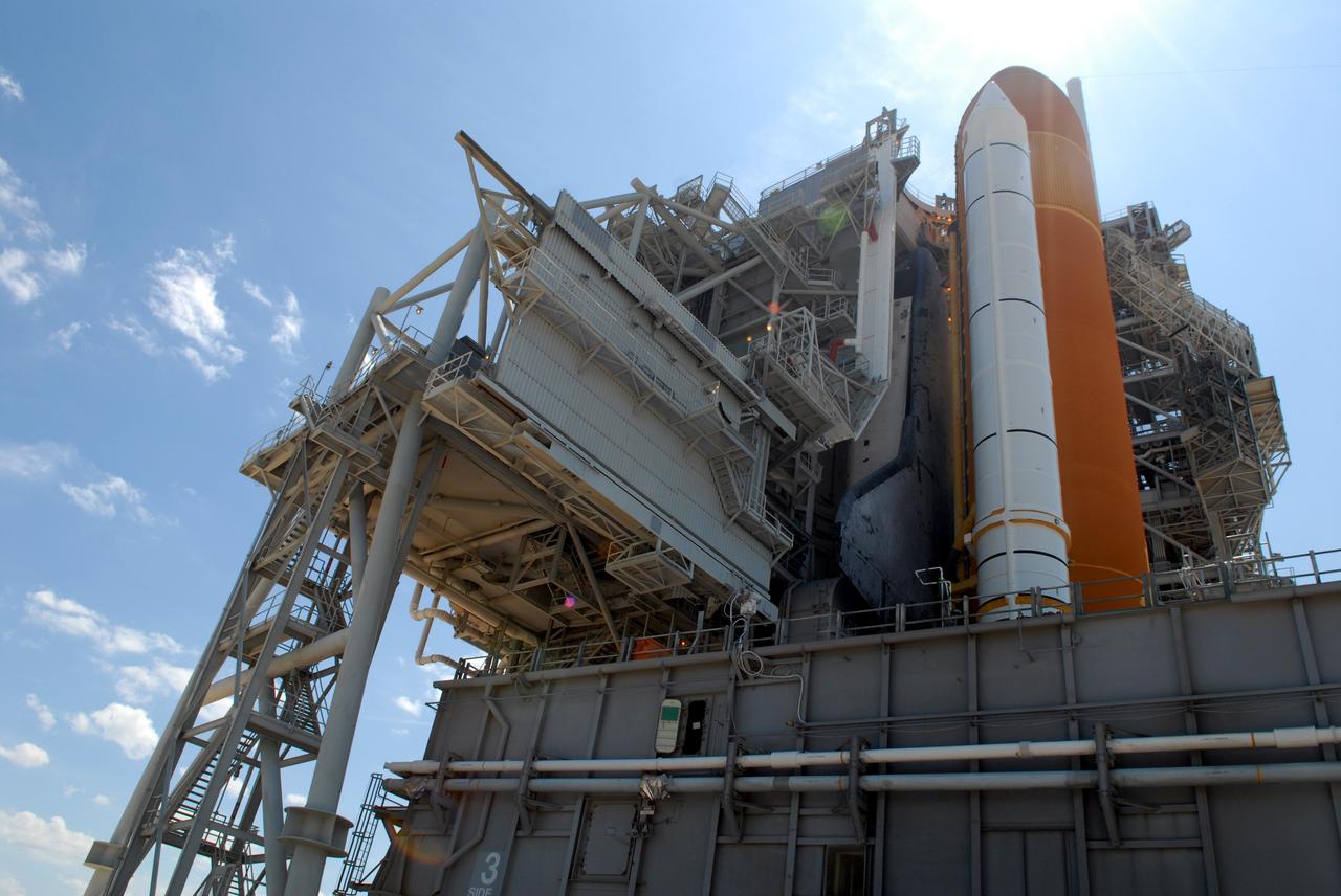 CAPE CANAVERAL, Fla. – Viewed from the side of Launch Pad 39A at NASA's Kennedy Space Center in Florida, the rotating service structure has been moved into place around space shuttle Endeavour. The RSS provides protected access to the shuttle for changeout and servicing of payloads at the pad. The structure is supported by a rotating bridge that pivots about a vertical axis on the west side of the pad's flame trench. The RSS rotates through 120 degrees (one-third of a circle) on a radius of 160 feet. Support for the outer end of the bridge is provided by two eight-wheel, motor-driven trucks that move along circular twin rails installed flush with the pad surface. The track crosses the flame trench on a permanent bridge. Endeavour is targeted to launch June 13 on its STS-127 mission to the International Space Station. Photo credit: NASA/Tim Jacobs
