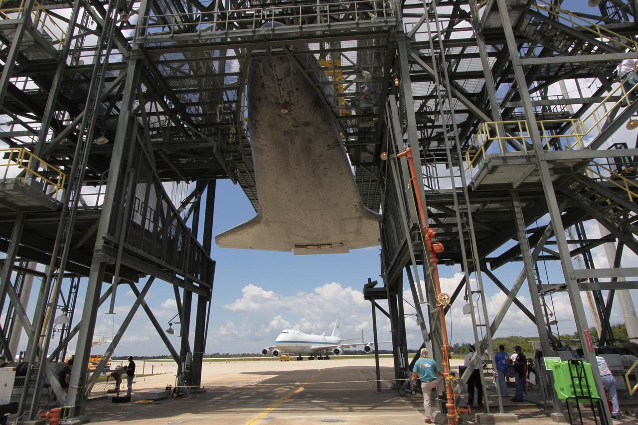 CAPE CANAVERAL, Fla. – On the Shuttle Landing Facility at NASA's Kennedy Space Center in Florida, space shuttle Atlantis remains suspended in the mate/demate device after the Shuttle Carrier Aircraft (below in the background) was moved away. Atlantis will be lowered to the ground via the hoist that is holding it. Atlantis returned from California atop the SCA, a modified Boeing 747, after its May 24 landing at Edwards Air Force Base, concluding mission STS-125. The ferry flight from Edwards Air Force Base began June 1. Atlantis' next assignment is the STS-129 mission, targeted to launch in November 2009. Photo credit: NASA/Jack Pfaller
