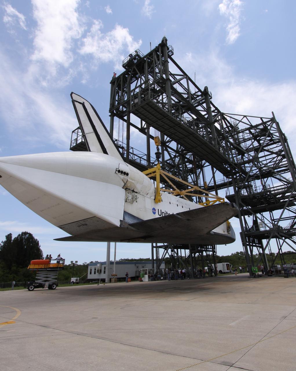 CAPE CANAVERAL, Fla. – On the Shuttle Landing Facility at NASA's Kennedy Space Center in Florida, space shuttle Atlantis is lowered toward the ground after being demated from the Shuttle Carrier Aircraft seen at left. Atlantis' wheels still must be lowered. Covering the rear of Atlantis is the tail cone, which protects the aft engine area and provides a more efficient aeronautical dimension during a piggyback flight. Atlantis returned from California atop the SCA, a modified Boeing 747, after its May 24 landing at Edwards Air Force Base, concluding mission STS-125. The ferry flight from Edwards Air Force Base began June 1. Atlantis' next assignment is the STS-129 mission, targeted to launch in November 2009. Photo credit: NASA/Jack Pfaller