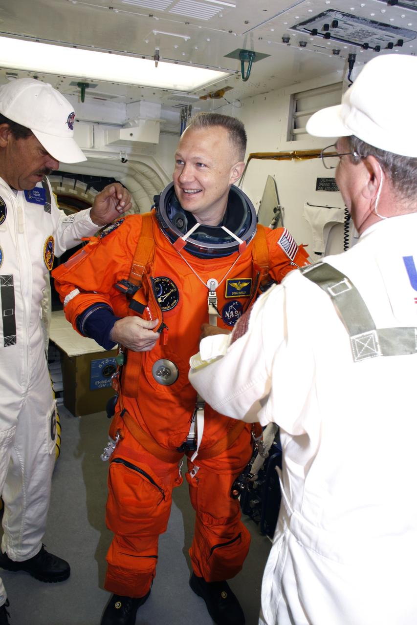 CAPE CANAVERAL, Fla. –  In the White Room on the orbiter access arm of the fixed service structure on Launch Pad 39A at NASA's Kennedy Space Center in Florida, STS-127 Pilot Doug Hurley is helped to secure the harness over his launch-and-entry suit.  He will enter space shuttle Endeavour for the simulated launch countdown.  The crew is at Kennedy for a launch dress rehearsal called the terminal countdown demonstration test, or TCDT, which includes the simulation, emergency exit training and equipment familiarization.  Endeavour's STS-127 mission is the final of three flights dedicated to the assembly of the Japanese Kibo laboratory complex on the International Space Station.  Endeavour's launch is scheduled for June 13 at 7:17 a.m. EDT.  Photo credit: NASA/Troy Cryder