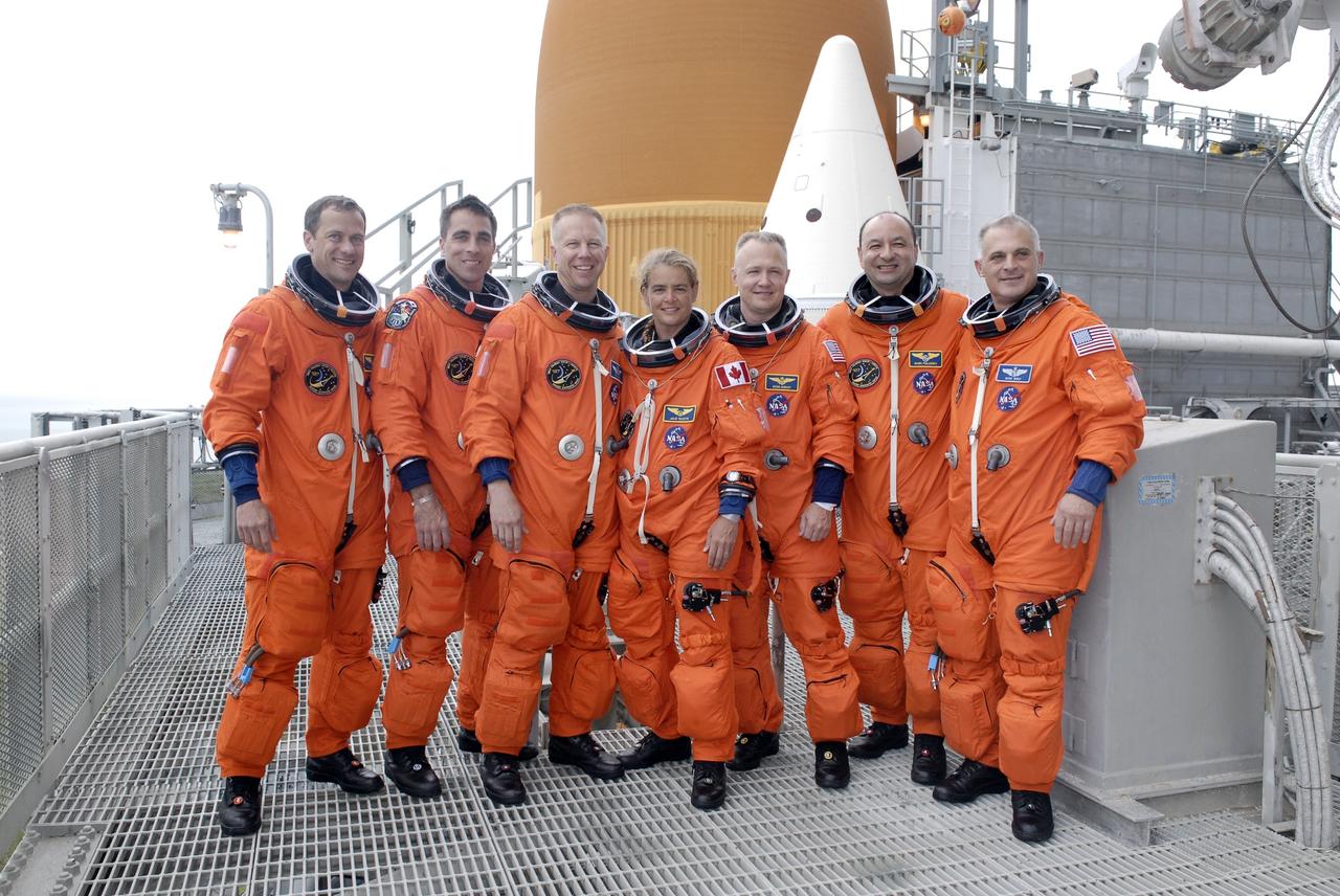 CAPE CANAVERAL, Fla. – The STS-127 crew members gather at the 225-foot level of the fixed service structure for a photo to commemorate the conclusion of the terminal countdown demonstration test, which ended with a simulated launch countdown.  From left are Mission Specialists Tom Marshburn, Christopher Cassidy, Tim Kopra and Julie Payette, Pilot Doug Hurley, Commander Mark Polansky and Mission Specialist Dave Wolf. Behind them are the tops of the orange external fuel tank and one of the two solid rocket boosters. Endeavour's STS-127 mission is the final of three flights dedicated to the assembly of the Japanese Kibo laboratory complex on the International Space Station.  Endeavour's launch is scheduled for June 13 at 7:17 a.m. EDT.   Photo credit: NASA/Kim Shiflett