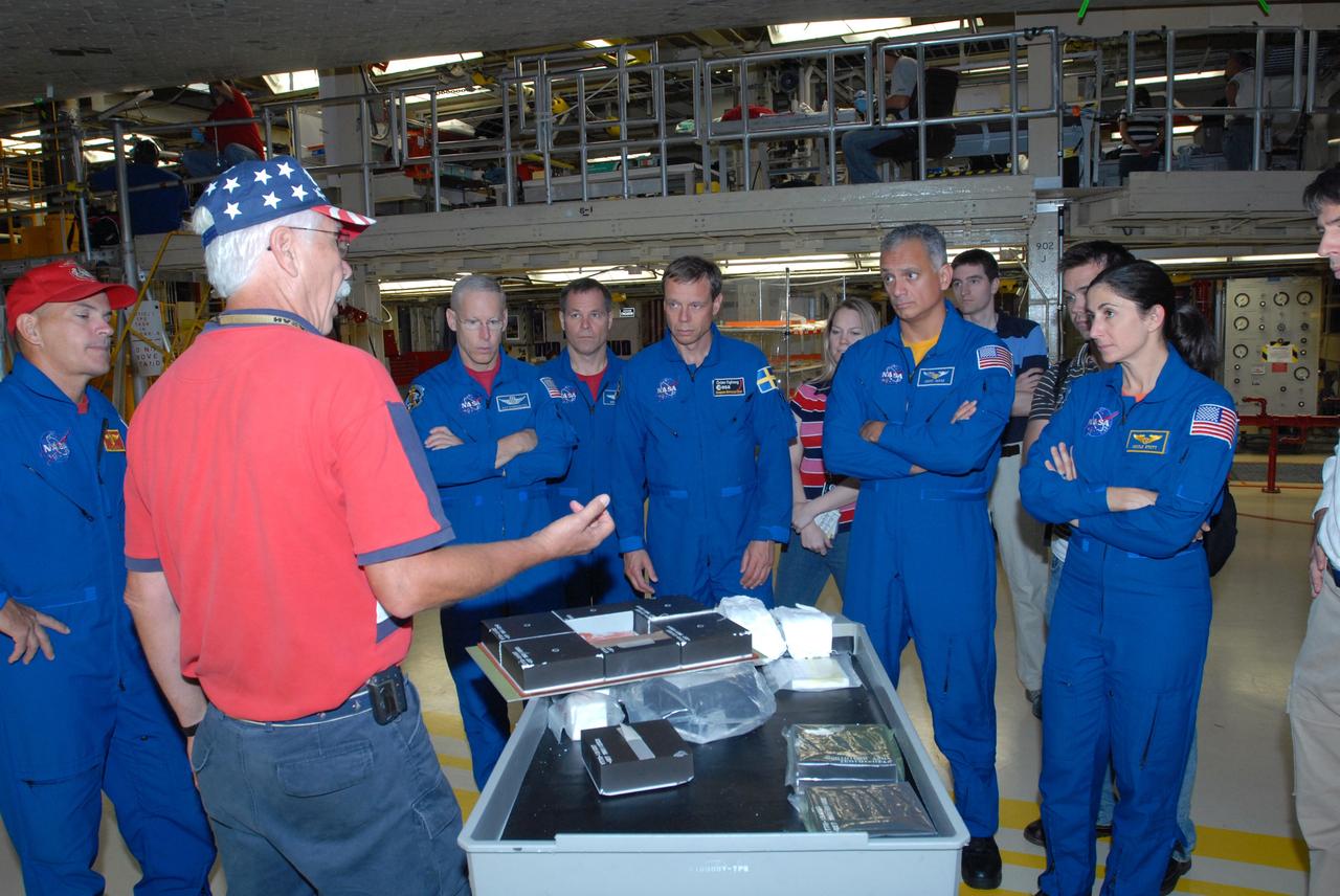 CAPE CANAVERAL, Fla. – In Orbiter Processing Facility 3 at NASA's Kennedy Space Center in Florida, STS-128 crew members listen to a tile expert while checking out space shuttle Discovery.   The astronauts are, from left, Commander Rick Sturckow, Mission Specialist Patrick Forrester, Pilot Kevin Ford, and Mission Specialists Christer Fuglesang, John "Danny" Olivas and Nicole Stott.  The crew is at Kennedy for a crew equipment interface test, or CEIT, which provides hands-on training and observation of shuttle and flight hardware. The STS-128 flight will carry science and storage racks to the International Space Station on Discovery.  Launch is targeted for Aug. 7.   Photo credit: NASA/Jim Grossmann