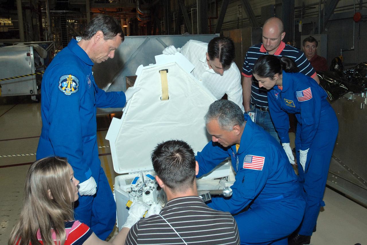 CAPE CANAVERAL, Fla. – In Orbiter Processing Facility 3 at NASA's Kennedy Space Center in Florida, STS-128 crew members check out storage containers they will use on the mission.  The astronauts are, from left, Mission Specialists Christer Fuglesang, John "Danny" Olivas and Nicole Stott. The crew is at Kennedy for a crew equipment interface test, or CEIT, which provides hands-on training and observation of shuttle and flight hardware. The STS-128 flight will carry science and storage racks to the International Space Station on Discovery.  Launch is targeted for Aug. 7.   Photo credit: NASA/Jim Grossmann