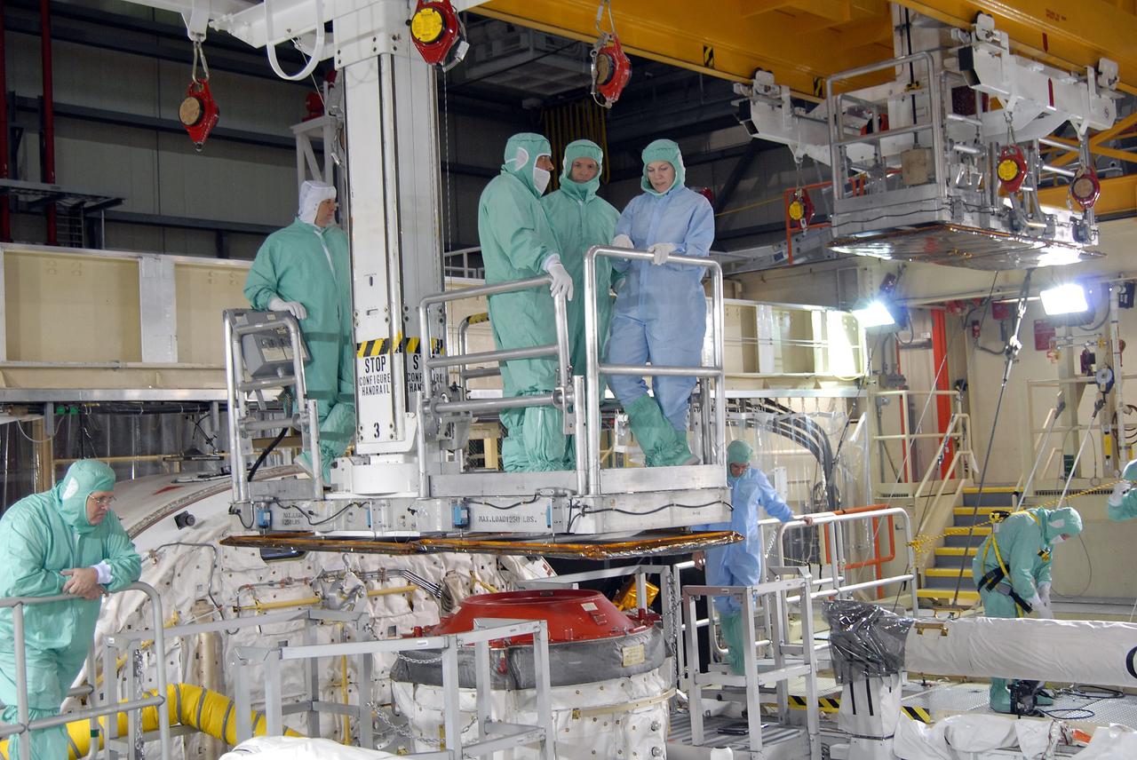 CAPE CANAVERAL, Fla. – In Orbiter Processing Facility 3 at NASA's Kennedy Space Center in Florida, STS-128 crew members are lowered into space shuttle Discovery's payload bay to check equipment.  At left is Mission Specialist Jose Hernandez; at center is Commander Rick Sturckow. The crew is at Kennedy for a crew equipment interface test, or CEIT, which provides hands-on training and observation of shuttle and flight hardware. The STS-128 flight will carry science and storage racks to the International Space Station on Discovery.  Launch is targeted for Aug. 7.   Photo credit: NASA/Jim Grossmann