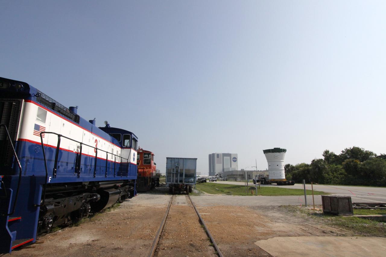 CAPE CANAVERAL, Fla. – At NASA's Kennedy Space Center in Florida, the Ares I-X forward assembly (comprising the frustum, forward skirt extension and forward skirt) moves alongside the NASA Railroad tracks as it heads for the Vehicle Assembly Building, in the background. In the VAB's High Bay 4, the forward assembly will undergo processing and stacking to the upper stage. Ares I-X is the flight test for the Ares I which will provide NASA an early opportunity to test and prove hardware, facilities and ground operations associated with Ares I, which is part of the Constellation Program to return men to the moon and beyond. Launch of the Ares I-X flight test is targeted for August 2009. Photo credit: NASA/Jack Pfaller