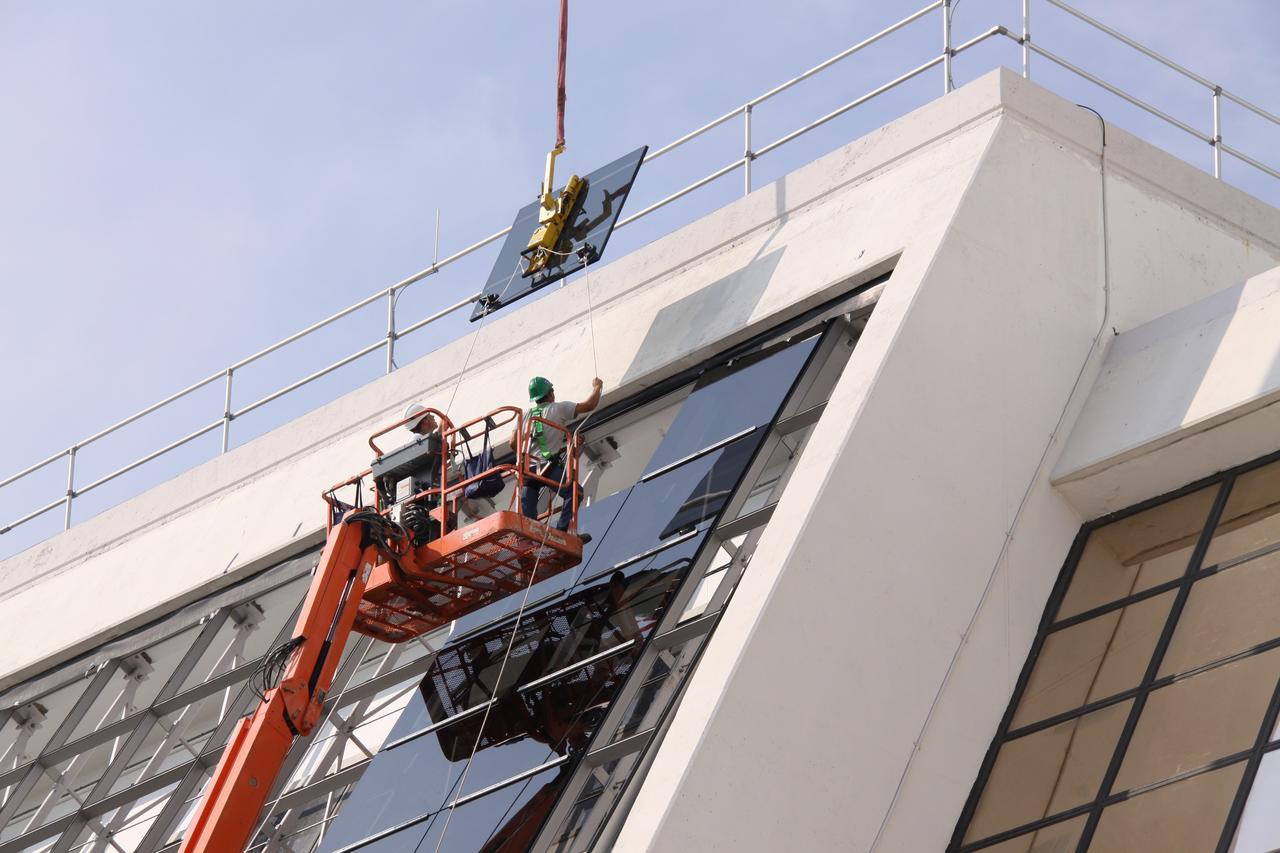 CAPE CANAVERAL, Fla. –  A new window is lowered toward the existing Firing Room windows in the Launch Control Center at NASA's Kennedy Space Center in Florida.  New, hurricane-rated window systems for the four Firing Rooms and the vestibule areas between Firing Rooms 1 & 2 and Firing Rooms 3 & 4 are being installed. In order to avoid operational impacts the new windows are being installed on the outside of the existing windows, enclosing the space formerly occupied by the louvers.  The old windows will remain in place until the new windows are completely installed and leak tested. This approach will continue to keep the firing rooms from being exposed to the elements.   Photo credit: NASA/Jack Pfaller