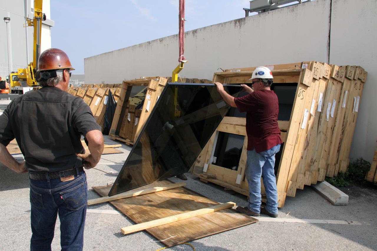 CAPE CANAVERAL, Fla. –  Alongside the Launch Control Center at NASA's Kennedy Space Center in Florida, a new window is prepared to be lifted up to the existing Firing Room windows.  New, hurricane-rated window systems for the four Firing Rooms and the vestibule areas between Firing Rooms 1 & 2 and Firing Rooms 3 & 4 are being installed. In order to avoid operational impacts the new windows are being installed on the outside of the existing windows, enclosing the space formerly occupied by the louvers.  The old windows will remain in place until the new windows are completely installed and leak tested. This approach will continue to keep the firing rooms from being exposed to the elements.   Photo credit: NASA/Jack Pfaller