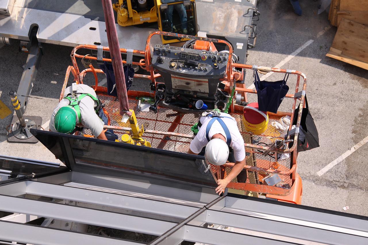 CAPE CANAVERAL, Fla. –  Workers at NASA's Kennedy Space Center in Florida carefully place a new window on the Firing Room in the Launch Control Center.  New, hurricane-rated window systems for the four Firing Rooms and the vestibule areas between Firing Rooms 1 & 2 and Firing Rooms 3 & 4 are being installed. In order to avoid operational impacts the new windows are being installed on the outside of the existing windows, enclosing the space formerly occupied by the louvers.  The old windows will remain in place until the new windows are completely installed and leak tested. This approach will continue to keep the firing rooms from being exposed to the elements.   Photo credit: NASA/Jack Pfaller