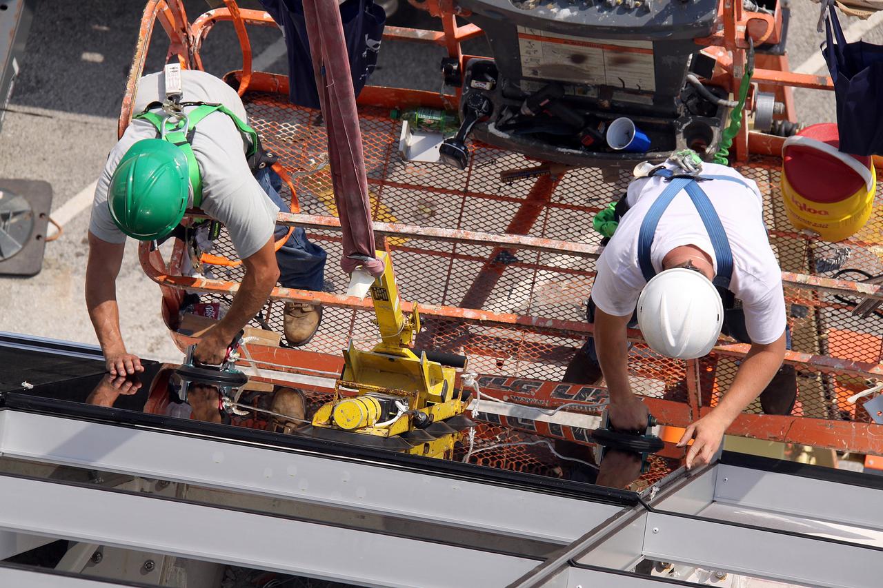CAPE CANAVERAL, Fla. –  Workers at NASA's Kennedy Space Center in Florida secure a new window on the Firing Room in the Launch Control Center.  New, hurricane-rated window systems for the four Firing Rooms and the vestibule areas between Firing Rooms 1 & 2 and Firing Rooms 3 & 4 are being installed. In order to avoid operational impacts the new windows are being installed on the outside of the existing windows, enclosing the space formerly occupied by the louvers.  The old windows will remain in place until the new windows are completely installed and leak tested. This approach will continue to keep the firing rooms from being exposed to the elements.   Photo credit: NASA/Jack Pfaller