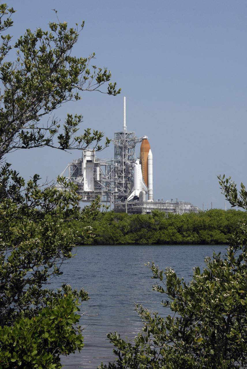 CAPE CANAVERAL, Fla. –  Framed by branches across the Indian River Lagoon, space shuttle Endeavour waits for launch after rollback of the rotating service structure, or RSS, at left. First motion of the RSS was at 10:15 a.m. EDT.  First motion of the RSS was at 10:15 a.m. EDT. The rollback is in preparation for Endeavour's liftoff on the STS-127 mission with a crew of seven.  This is the second launch attempt for Endeavour after the June 13 launch was scrubbed due to a hydrogen leak at the Ground Umbilical Carrier Plate during tanking June 12.  The launch will be Endeavour's 23rd flight. The shuttle will carry the Japanese Experiment Module's Exposed Facility, or JEM-EF, and the Experiment Logistics Module-Exposed Section, or ELM-ES, on STS-127. The mission is the final of three flights dedicated to the assembly of the Japan Aerospace Exploration Agency's Kibo laboratory complex on the space station. Endeavour's launch is scheduled for June 17 at 5:40 a.m. EDT.  Photo credit: NASA/Kim Shiflett
