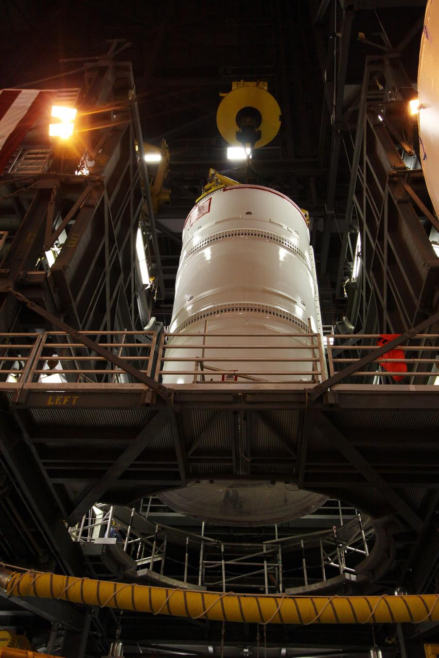 CAPE CANAVERAL, Fla. –  In the Vehicle Assembly Building at NASA's Kennedy Space Center in Florida, the Ares I-X fifth segment simulator assembly is lowered through a work platform in High Bay 4.  Ares I-X is the flight test vehicle for the Ares I,  the essential core of a safe, reliable, cost-effective space transportation system that eventually will carry crewed missions back to the moon, on to Mars and out into the solar system. Ares I-X is targeted for launch in August 2009.   Photo credit: NASA/Kim Shiflett