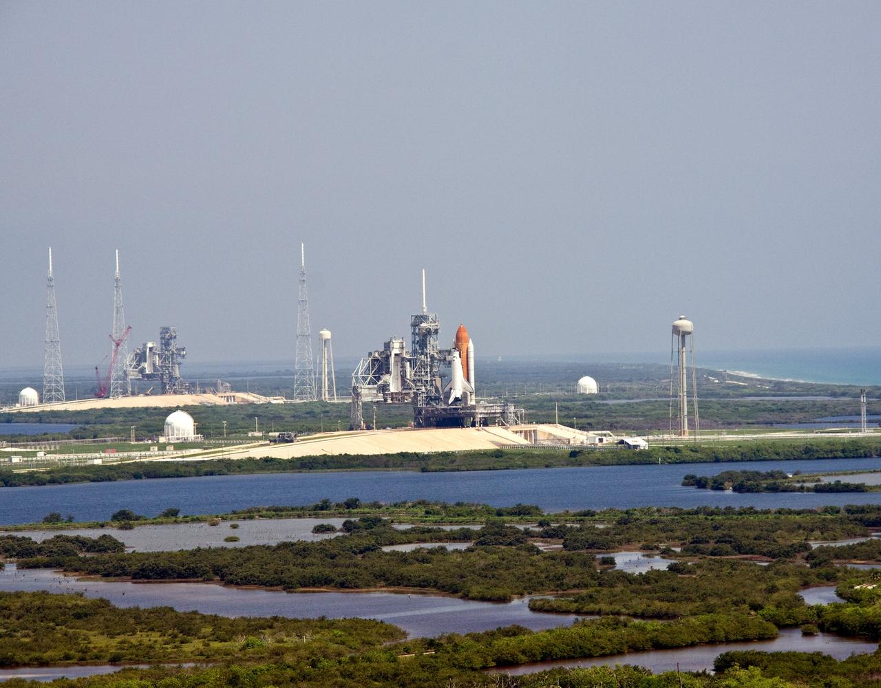 CAPE CANAVERAL, Fla. – Space Shuttle Endeavour (center) is still on launch Pad 39A midday after the launch for the STS-127 mission was scrubbed at 1:55 a.m. EDT June 17 due to a gaseous hydrogen leak at the Ground Umbilical Carrier Plate, the same cause for the June 13 delay. On the left is Launch Pad 39B, surrounded by lightning towers, which will be used for the Constellation Program. Endeavour’s next launch attempt for the mission is targeted for July 11 at 7:39 p.m. EDT. Photo credit: NASA/Jack Pfaller