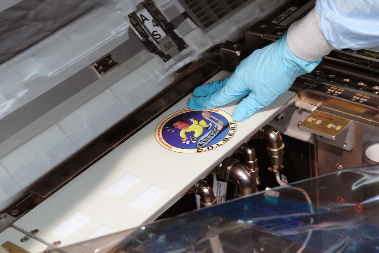 CAPE CANAVERAL, Fla. – The C.O.L.B.E.R.T decal is placed on the Combined Operational Load Bearing External Resistance Treadmill.  The treadmill shares space in the Leonardo multi-purpose logistics module in the Space Station Processing Facility at NASA's Kennedy Space Center in Florida.  The module is part of the payload for the STS-128 mission to the International Space Station aboard space shuttle Discovery.  The treadmill is named after comedian Stephen Colbert, the host of Comedy Central’s “The Colbert Report.” Colbert urged his viewers to suggest the name “Colbert” as the name for the station’s Node 3 module. Although his name did receive the most entries in an Internet polling contest, NASA chose the name “Tranquility” to honor the accomplishments of the Apollo 11 mission. COLBERT will be installed in Tranquility after the node arrives at the station next year. Launch of STS-128 is targeted for Aug. 7, 2009.  Photo credit: NASA/Jim Grossmann