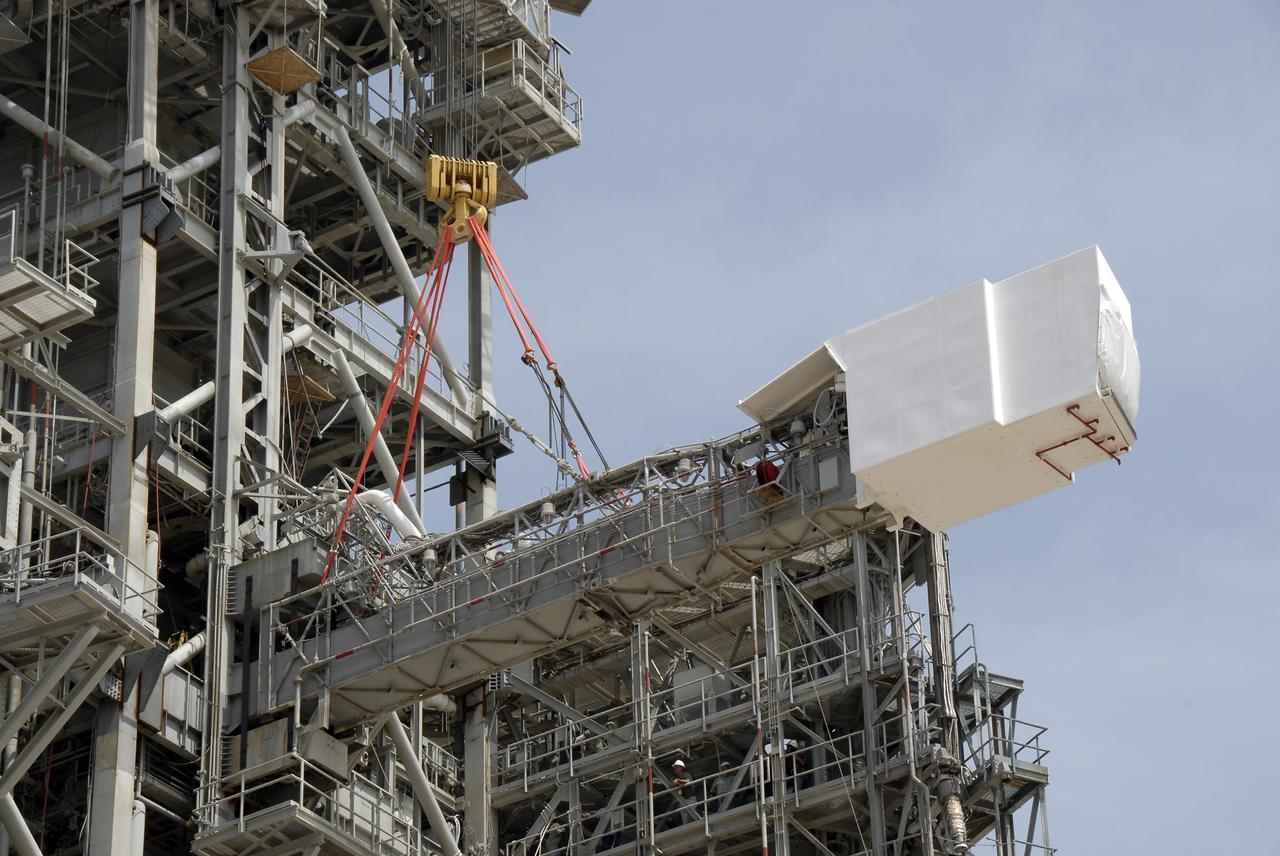 CAPE CANAVERAL, Fla. – The slings from a large crane are in place on the orbiter access arm, which ends in the White Room, that is part of the fixed service structure, or FSS, on Launch Pad 39B at NASA's Kennedy Space Center in Florida. The White Room provided entry into space shuttles that were on the pad. The arm is being removed from the FSS for the pad's conversion as launch site for the Constellation Program's Ares I-X. The launch of the Ares I-X flight test is targeted for August 2009. Photo credit: NASA/Kim Shiflett