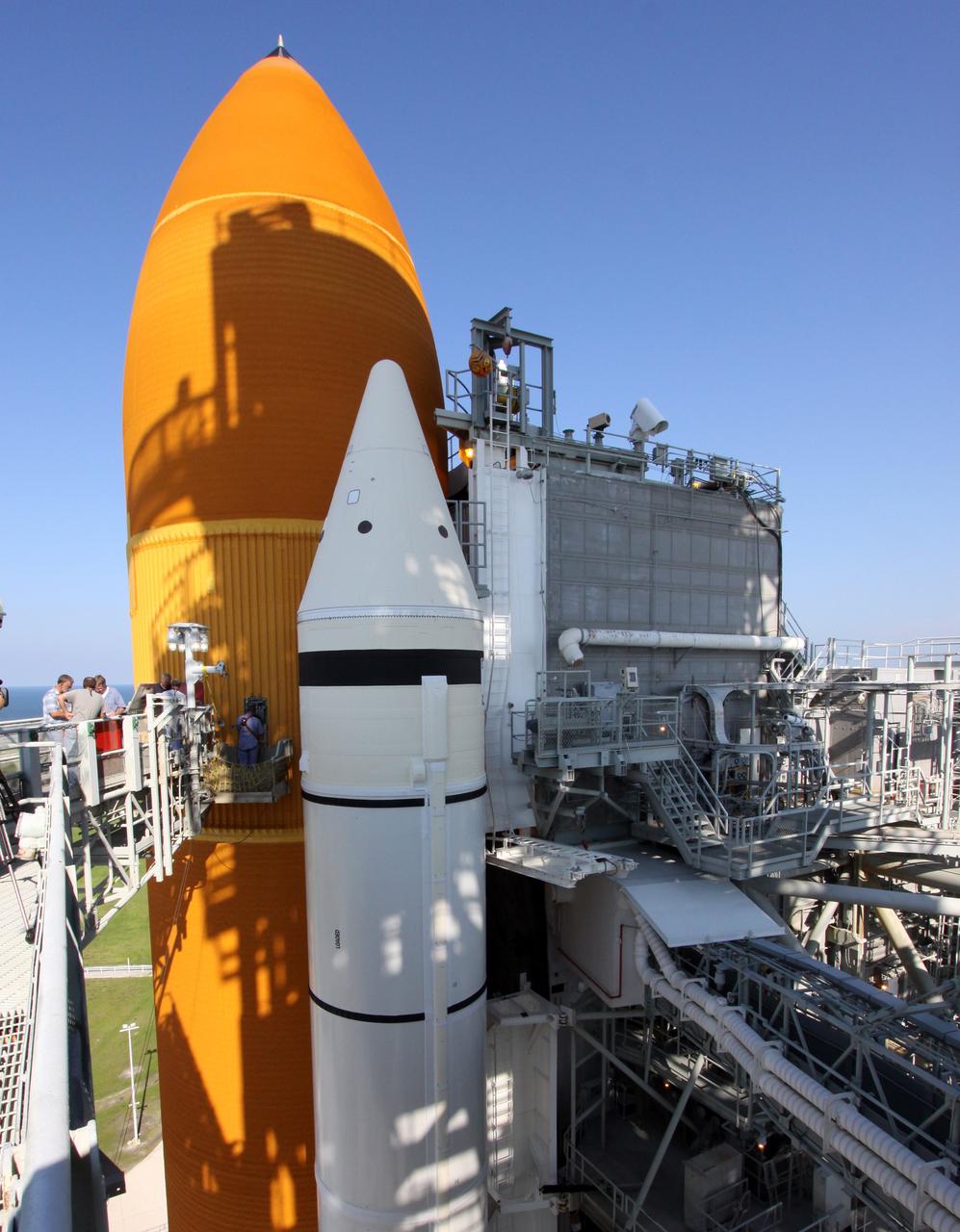 CAPE CANAVERAL, Fla. – The afternoon sun casts shadows on space shuttle Endeavour's external fuel tank as workers remove the seal from the Ground Umbilical Carrier Plate, or GUCP, on the tank. A hydrogen leak at the location during tanking for the STS-127 mission caused the launch attempts to be scrubbed on June 13 and June 17. The GUCP will be examined to determine the cause of the hydrogen leak and repaired. The GUCP is the overboard vent to the pad and the flame stack where the vented hydrogen is burned off. Endeavour's next launch attempt is targeted for July 11 at 7:39 p.m. EDT. Photo credit: NASA/Jack Pfaller