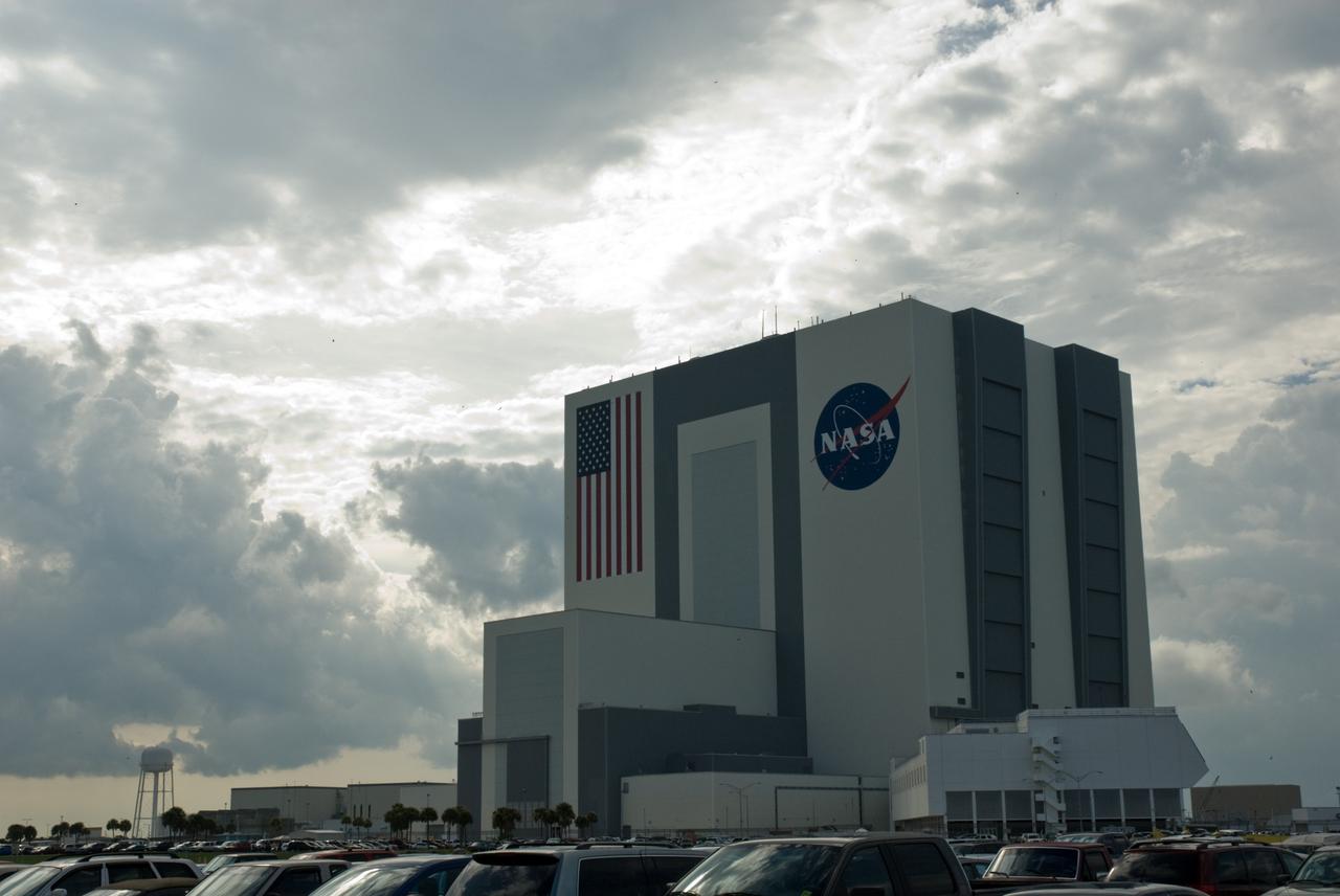 CAPE CANAVERAL, Fla. – Dark clouds fill the sky behind the Vehicle Assembly Building at NASA's Kennedy Space Center in Florida.  NASA managers postponed today’s space shuttle launch because of lightning and thunderstorms within the 20-nautical-mile circle around the launch pad. The fifth launch attempt for the STS-127 mission was scrubbed at 6:39 p.m. EDT. The first two launch attempts on June 13 and June 17 were scrubbed when a hydrogen gas leak occurred during tanking due to a misaligned Ground Umbilical Carrier Plate. Mission managers also decided to delay tanking on July 11 for a launch attempt later in the day to allow engineers and safety personnel time to analyze data captured during lightning strikes near the pad on July 10. Weather concerns caused a scrub July 12 as well. Endeavour will deliver the Japanese Experiment Module's Exposed Facility, or JEM-EF, and the Experiment Logistics Module-Exposed Section, or ELM-ES, in the final of three flights dedicated to the assembly of the Japan Aerospace Exploration Agency's Kibo laboratory complex on the International Space Station.  STS-127 is the 29th flight for the assembly of the space.    Photo credit: NASA/Tim Jacobs