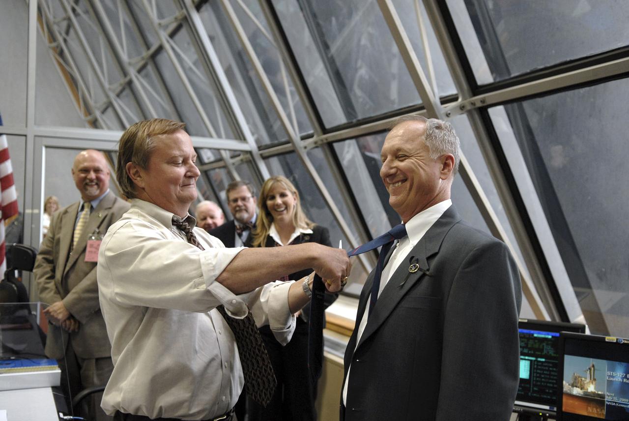 CAPE CANAVERAL, Fla. – In the Firing Room at NASA's Kennedy Space Center in Florida, Shuttle Launch Director Mike Leinbach  performs the traditional tie-cutting of the inaugural launch for STS-127 Shuttle Launch Director Pete Nickolenko .  Liftoff of space shuttle Endeavour on the STS-127 mission was on-time at 6:03 p.m. EDT.  Today was the sixth launch attempt for the STS-127 mission.  The launch was scrubbed on June 13 and June 17 when a hydrogen gas leak occurred during tanking due to a misaligned Ground Umbilical Carrier Plate.  The mission was postponed July 11, 12 and 13 due to weather conditions near the Shuttle Landing Facility at Kennedy that violated rules for launching, and lightning issues. Endeavour will deliver the Japanese Experiment Module's Exposed Facility and the Experiment Logistics Module-Exposed Section in the final of three flights dedicated to the assembly of the Japan Aerospace Exploration Agency's Kibo laboratory complex on the International Space Station.   Photo credit: NASA/Kim Shiflett