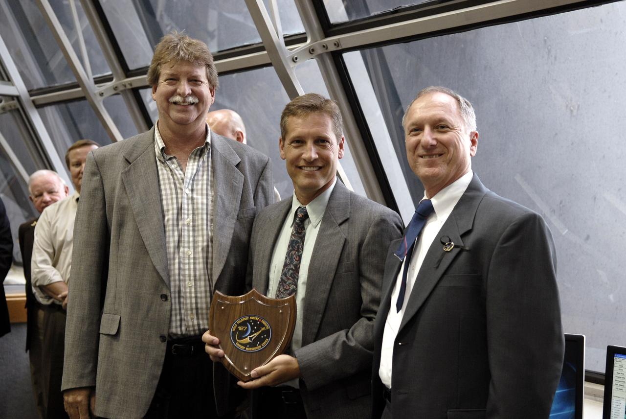 CAPE CANAVERAL, Fla. –  In the Firing Room at NASA's Kennedy Space Center in Florida,  Tom Mears (left) and David Sutherland (center) receive a plaque for their efforts in the successful launching of space shuttle Endeavour on the STS-127 mission.  At right is the STS-127 Shuttle Launch Director Pete Nickolenko.  Endeavour lifted off on-time at 6:03 p.m. EDT. This was the sixth launch attempt for the STS-127 mission.  The launch was scrubbed on June 13 and June 17 when a hydrogen gas leak occurred during tanking due to a misaligned Ground Umbilical Carrier Plate.  The mission was postponed July 11, 12 and 13 due to weather conditions near the Shuttle Landing Facility at Kennedy that violated rules for launching, and lightning issues. Endeavour will deliver the Japanese Experiment Module's Exposed Facility and the Experiment Logistics Module-Exposed Section in the final of three flights dedicated to the assembly of the Japan Aerospace Exploration Agency's Kibo laboratory complex on the International Space Station.   Photo credit: NASA/Kim Shiflett