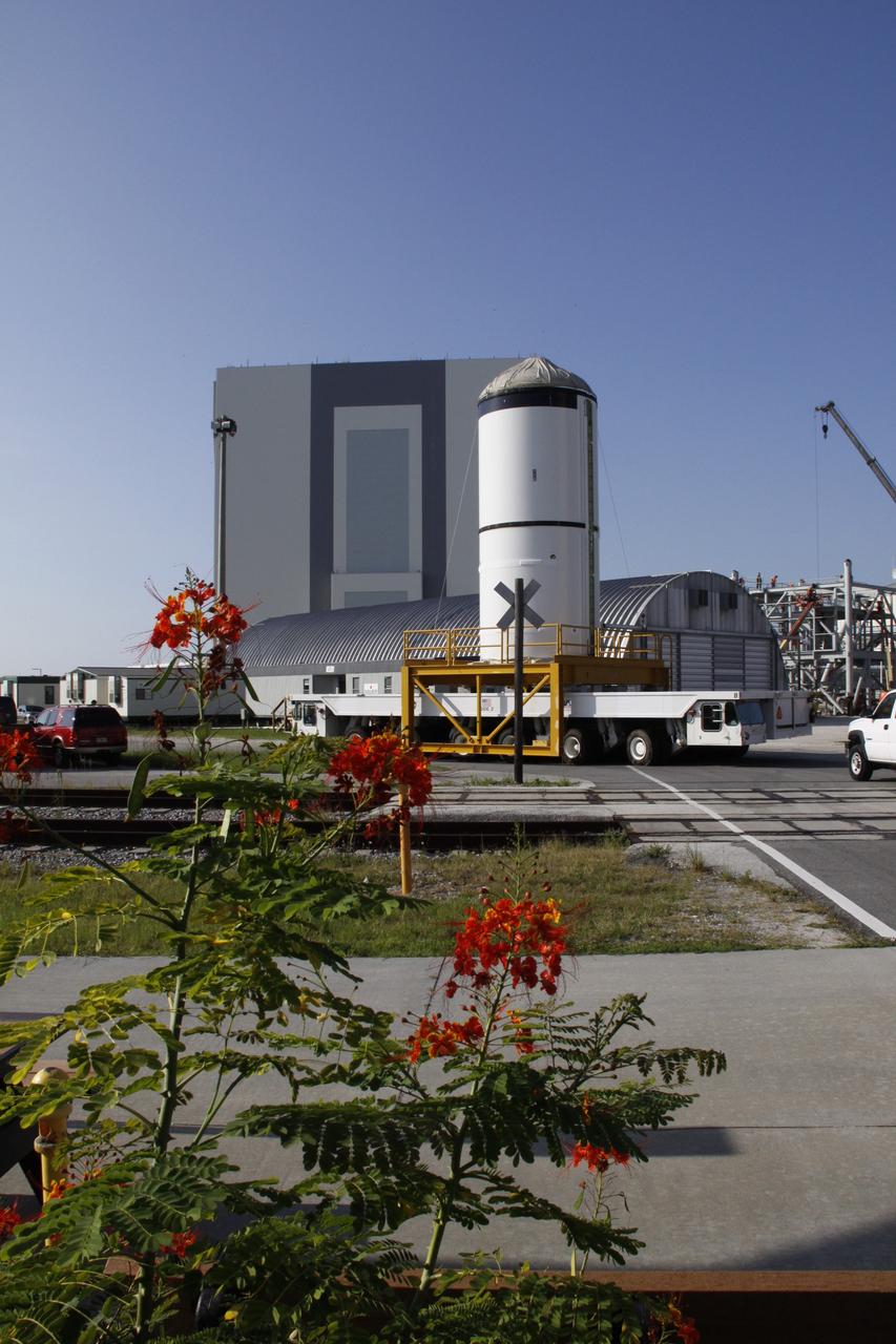 CAPE CANAVERAL, Fla. – The Ares I-X forward segment leaves the Rotation, Surge and Processing Facility at NASA's Kennedy Space Center in Florida. It is being transported to the Vehicle Assembly Building, which is in the background, for mating with the aft center and aft segments already stacked. Part of the Constellation Program, the Ares I-X is the test vehicle for the Ares I, which is the essential core of a space transportation system that eventually will carry crewed missions back to the moon, on to Mars and out into the solar system . The Ares I-X flight test is targeted for no earlier than Aug. 30. Photo credit: NASA/Troy Cryder