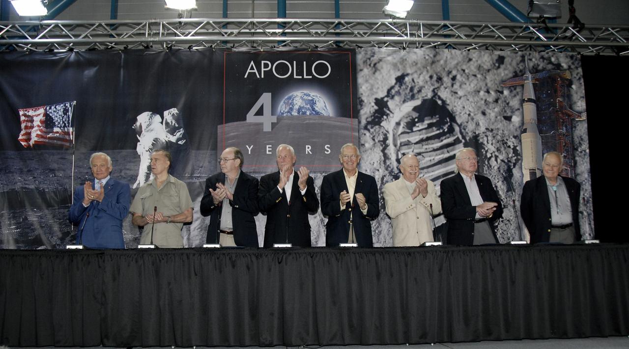 CAPE CANAVERAL, Fla. –  At the Apollo/Saturn V Center at NASA's Kennedy Space Center in Florida, Apollo astronauts (from left) Buzz Aldrin, Walt Cunningham, Edgar Mitchell, Al Worden, Charlie Duke, Vance Brand and Gerald Carr applaud the addition of Apollo astronaut Bruce McCandless on stage for NASA's 40th Anniversary of Apollo Celebration of the July 1969 launch and landing on the moon.  McCandless  was a member of the astronaut support crew for the Apollo 14 mission and was backup pilot for the first manned Skylab mission. Among other accomplishments, he collaborated on the development of the Manned Maneuvering Unit used during shuttle EVAs.  Photo credit: NASA/Kim Shiflett