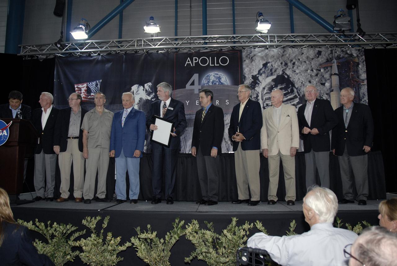 CAPE CANAVERAL, Fla. – During NASA's 40th Anniversary of Apollo Celebration at the Apollo/Saturn V Center at NASA's Kennedy Space Center in Florida, Center Director Bob Cabana (center) and Chief Operating Officer of the Kennedy Space Center Visitor Complex Bob Moore (left of Cabana) join Apollo astronauts on the stage.  At far left is the program moderator John Zarella, with CNN. The astronauts are (from left) Al Worden, Edgar Mitchell, Walt Cunningham, Buzz Aldrin, (Moore, Cabana), Charlie Duke, Vance Brand, Gerald Carr and Bruce McCandless. The celebration honored the July 1969 launch and landing on the moon.  Photo credit: NASA/Kim Shiflett