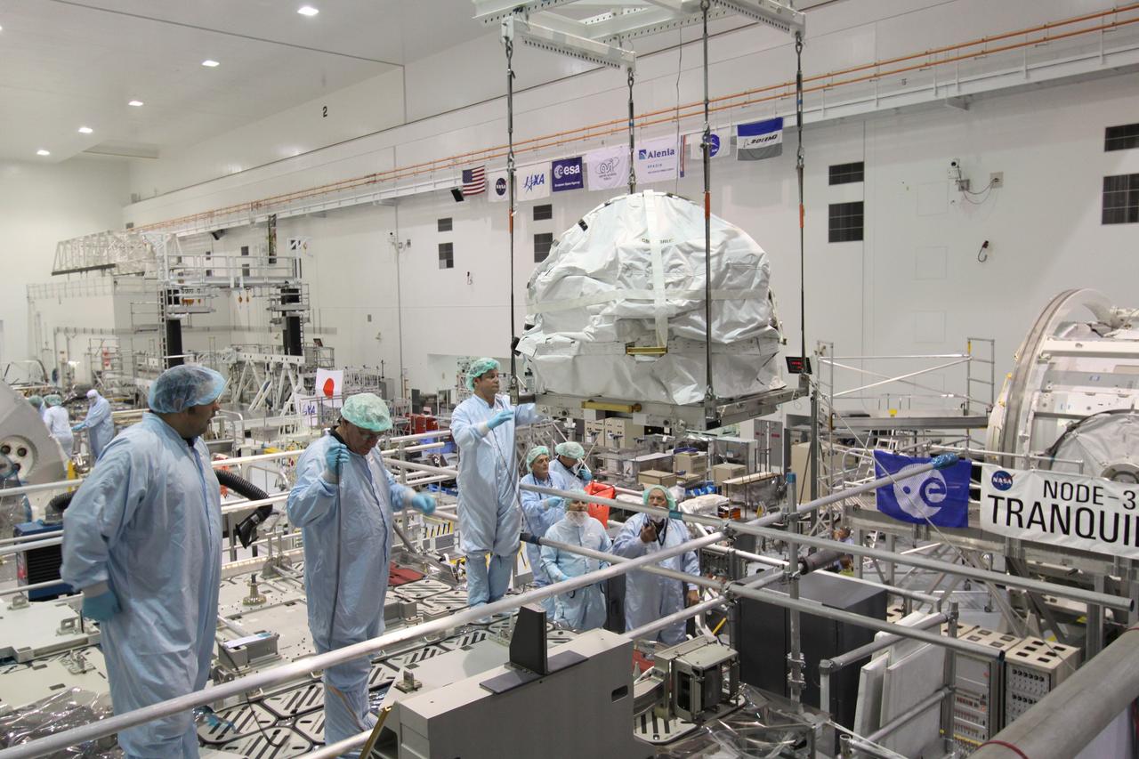 CAPE CANAVERAL, Fla. – In the Space Station Processing Facility at NASA's Kennedy Space Center in Florida,  technicians keep watch as the control moment gyroscope is moved toward an EXPRESS Logistics Carrier.  The carrier is part of the STS-129 payload on space shuttle Atlantis, which will deliver to the International Space Station two spare gyroscopes, two nitrogen tank assemblies, two pump modules, an ammonia tank assembly and a spare latching end effector for the station's robotic arm.  STS-129 is targeted to launch Nov. 12 .  Photo credit: NASA/Jack Pfaller