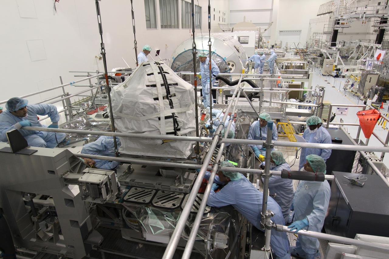 CAPE CANAVERAL, Fla. – In the Space Station Processing Facility at NASA's Kennedy Space Center in Florida,  technicians keep watch as the control moment gyroscope is lowered toward an EXPRESS Logistics Carrier.  The carrier is part of the STS-129 payload on space shuttle Atlantis, which will deliver to the International Space Station two spare gyroscopes, two nitrogen tank assemblies, two pump modules, an ammonia tank assembly and a spare latching end effector for the station's robotic arm.  STS-129 is targeted to launch Nov. 12 .  Photo credit: NASA/Jack Pfaller