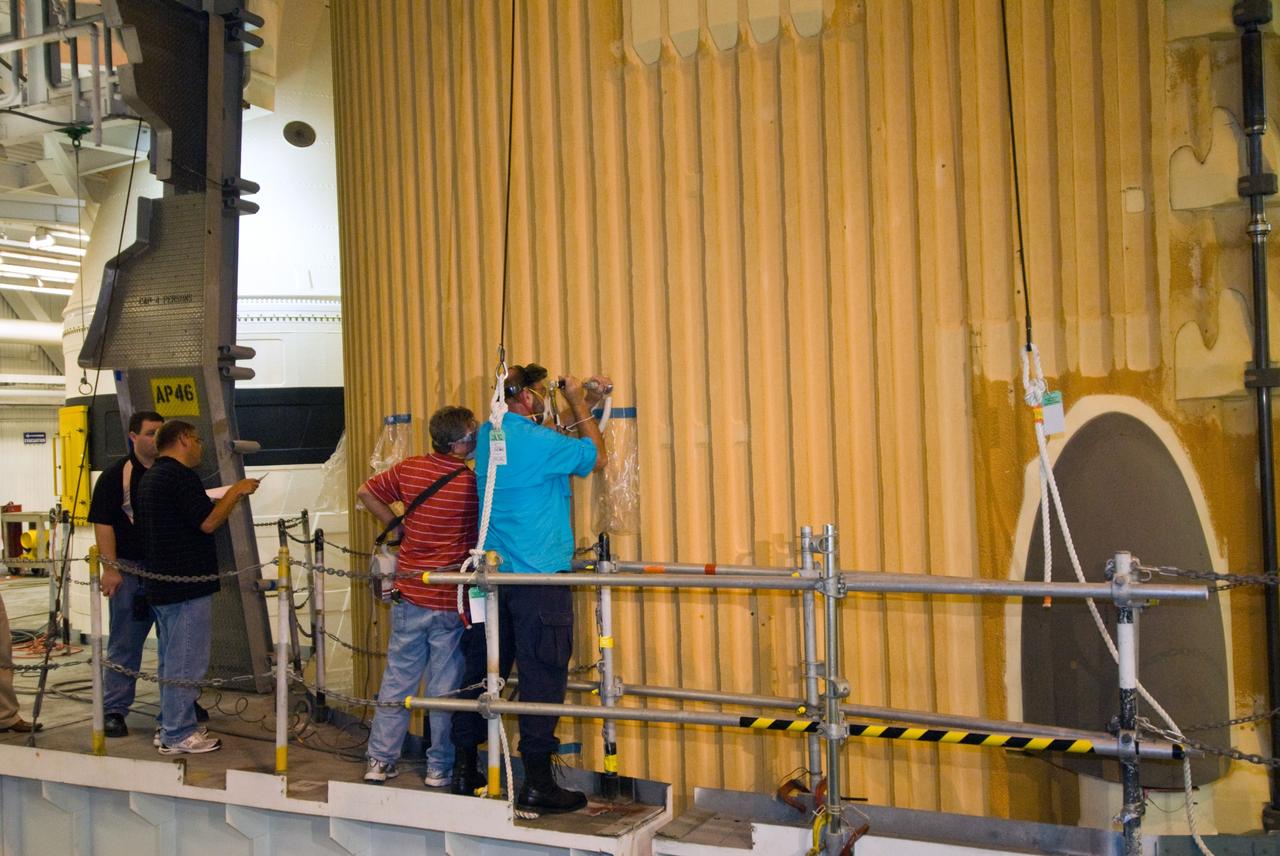 CAPE CANAVERAL, Fla. – In the Vehicle Assembly Building's  High Bay 1 at NASA's Kennedy Space Center in Florida, workers are testing foam adhesion on the intertank of space shuttle Discovery's  external tank.  At right are Eugene Sweet (red shirt), principal liaison engineer, and David Buras, a Material and Process engineer from NASA's Michoud Assembly Facility near New Orleans where the fuel tanks are built. They are collecting 26 foam samples an inch-and-half in diameter for analysis to confirm the foam is bonded well to the metal primer underneath. The testing was prompted by the foam loss during launch of space shuttle Endeavour on the STS-127 mission July 15. Samples are being sent to Michoud for study.  Photo credit: NASA/Tim Jacobs