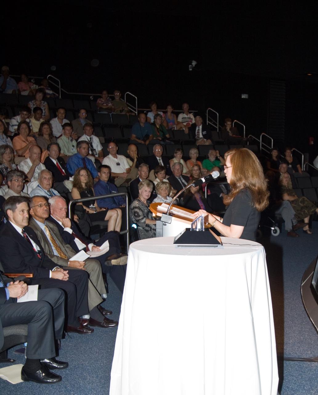 CAPE CANAVERAL, Fla. – At NASA's Kennedy Space Center in Florida, External Relations Director Lisa Malone speaks to an audience in Kennedy's Visitor Complex about the Ambassador of Exploration Award being given to Al Worden, an Apollo astronaut. Worden is being honored for his contributions to the U.S. space program. The award, to be displayed at Kennedy, is a moon rock encased in Lucite, mounted for public display. Worden served as command module pilot for the Apollo 15 mission, which set several moon records for NASA, including the longest lunar surface stay time, the longest lunar extravehicular activity and the first use of a lunar roving vehicle. Worden spent 38 minutes in a spacewalk outside the command module and logged a total of 295 hours, 11 minutes in space during the mission. NASA is giving the Ambassador of Exploration Award to the first generation of explorers in the Mercury, Gemini and Apollo space programs for realizing America's goal of going to the moon. The rock is part of the 842 pounds of lunar samples collected during six Apollo expeditions from 1969 to 1972. Those astronauts who receive the award will then present the award to a museum of their choice. Photo credit: NASA/Jack Pfaller