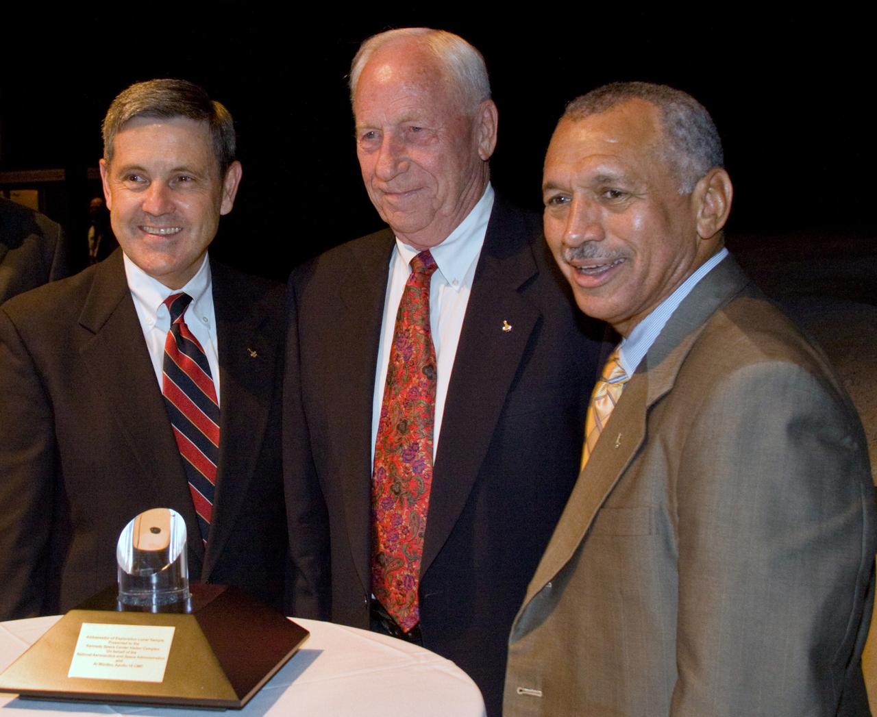 CAPE CANAVERAL, Fla. – At NASA Kennedy Space Center's Visitor Complex in Florida, Apollo astronaut Al Worden (center) is flanked by Center Director Bob Cabana (left) and NASA Administrator Charles Bolden.  Worden was presented with the Ambassador of Exploration Award to honor his contributions to the U.S. space program. A moon rock encased in Lucite, the award is seen in the foreground and will be displayed at Kennedy. Worden served as command module pilot for the Apollo 15 mission, which set several moon records for NASA, including the longest lunar surface stay time, the longest lunar extravehicular activity and the first use of a lunar roving vehicle. Worden spent 38 minutes in a spacewalk outside the command module and logged a total of 295 hours, 11 minutes in space during the mission. NASA is giving the Ambassador of Exploration Award to the first generation of explorers in the Mercury, Gemini and Apollo space programs for realizing America's goal of going to the moon. The rock is part of the 842 pounds of lunar samples collected during six Apollo expeditions from 1969 to 1972. Those astronauts who receive the award will then present the award to a museum of their choice. Photo credit: NASA/Jack Pfaller