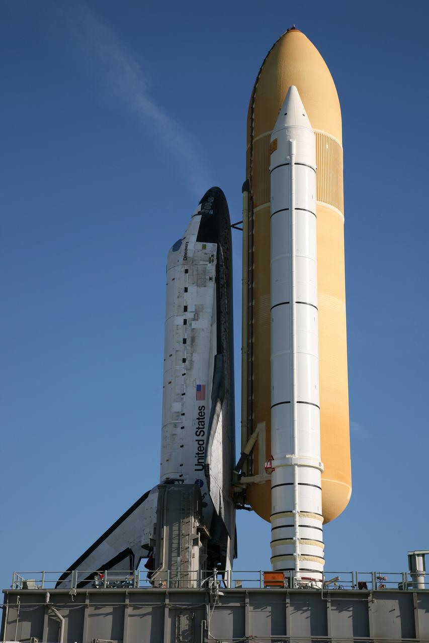 CAPE CANAVERAL, Fla. – Cast in shadow by the external fuel tank blocking the morning sun, space shuttle Discovery makes its way to Launch Pad 39A at NASA's Kennedy Space Center in Florida. The 3.4-mile journey was slower than usual as technicians stopped several times to clear mud from the crawler's treads and bearings caused by the waterlogged crawlerway. First motion out of the Vehicle Assembly Building was at 2:07 a.m. EDT Aug. 4. Rollout was delayed approximately 2 hours due to lightning in the area. Discovery's 13-day flight will deliver a new crew member and 33,000 pounds of equipment to the International Space Station. The equipment includes science and storage racks, a freezer to store research samples, a new sleeping compartment and the COLBERT treadmill. Launch of Discovery on its STS-128 mission is targeted for late August. Photo credit: NASA/Dimitri Gerondidakis