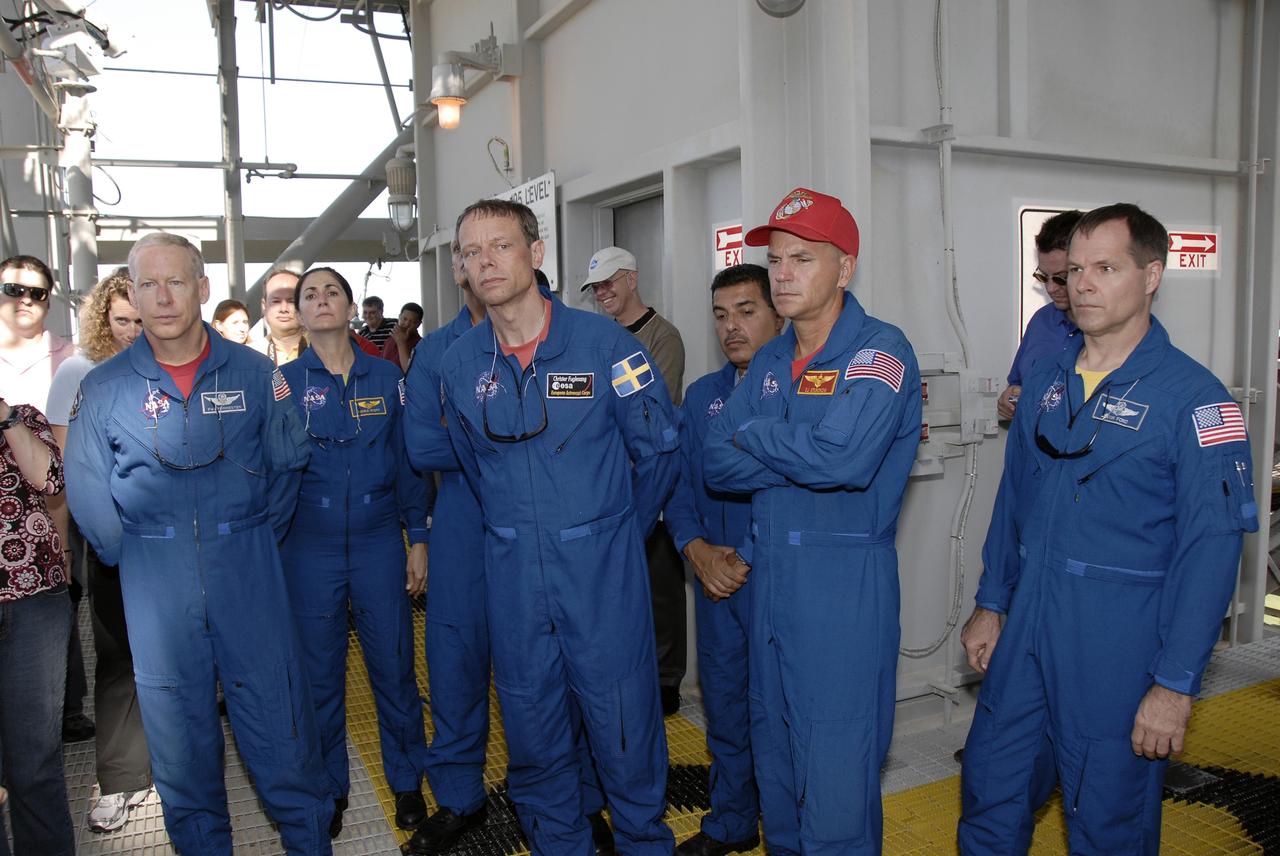 CAPE CANAVERAL, Fla. –  At NASA's Kennedy Space Center in Florida, STS-128 crew members get instructions about using slidewire baskets for emergency exit from the fixed service structure on Launch Pad 39A.  From left are Mission Specialist Patrick Forrester, Nicole Stott, Christer Fuglesang and Jose Hernandez, Commander Rick Sturckow and Pilot Kevin Ford. The crew is at Kennedy for a launch dress rehearsal called the terminal countdown demonstration test, or TCDT, which includes emergency exit training and equipment familiarization, as well as a simulated launch countdown.  Discovery will deliver 33,000 pounds of equipment to the station, including science and storage racks, a freezer to store research samples, a new sleeping compartment and the COLBERT treadmill. Photo credit: NASA/Kim Shiflett