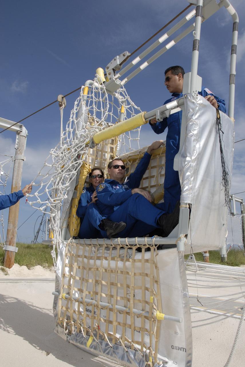 CAPE CANAVERAL, Fla. – STS-128 crew members practice getting out of a slidewire basket that can be used for emergency exit from Launch Pad 39A at NASA's Kennedy Space Center in Florida.  From left are Mission Specialist Nicole Stott, Pilot Kevin Ford and Mission Specialist Jose Hernandez.  The crew is at Kennedy for a launch dress rehearsal called the terminal countdown demonstration test, or TCDT, which includes emergency exit training and equipment familiarization, as well as a simulated launch countdown.  Discovery will deliver 33,000 pounds of equipment to the station, including science and storage racks, a freezer to store research samples, a new sleeping compartment and the COLBERT treadmill. Photo credit: NASA/Kim Shiflett